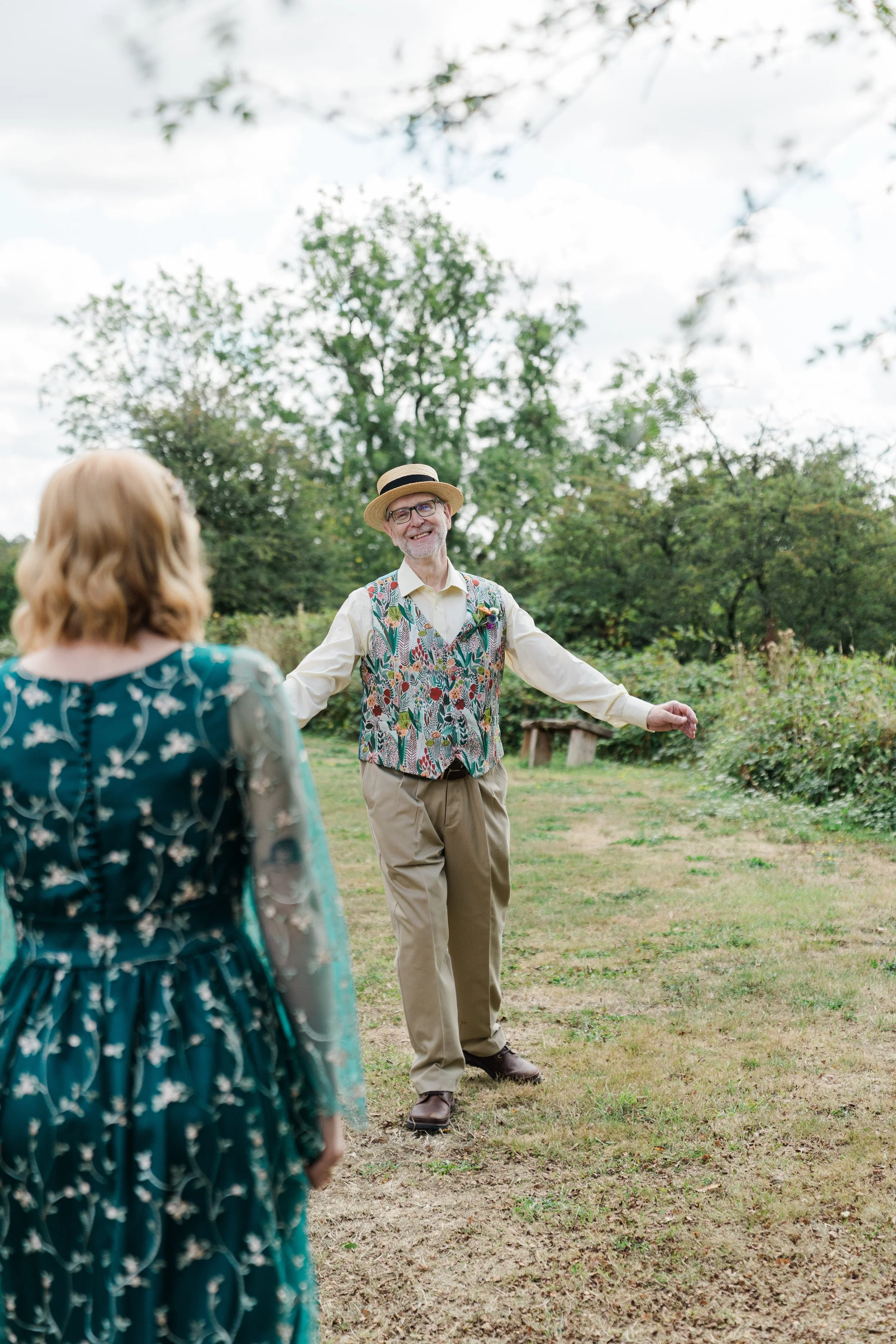 Father of Bride and see's bride for first time before wedding ceremony at Lapwing Farm. They are surrounded by greenery and trees under a partly cloudy sky.