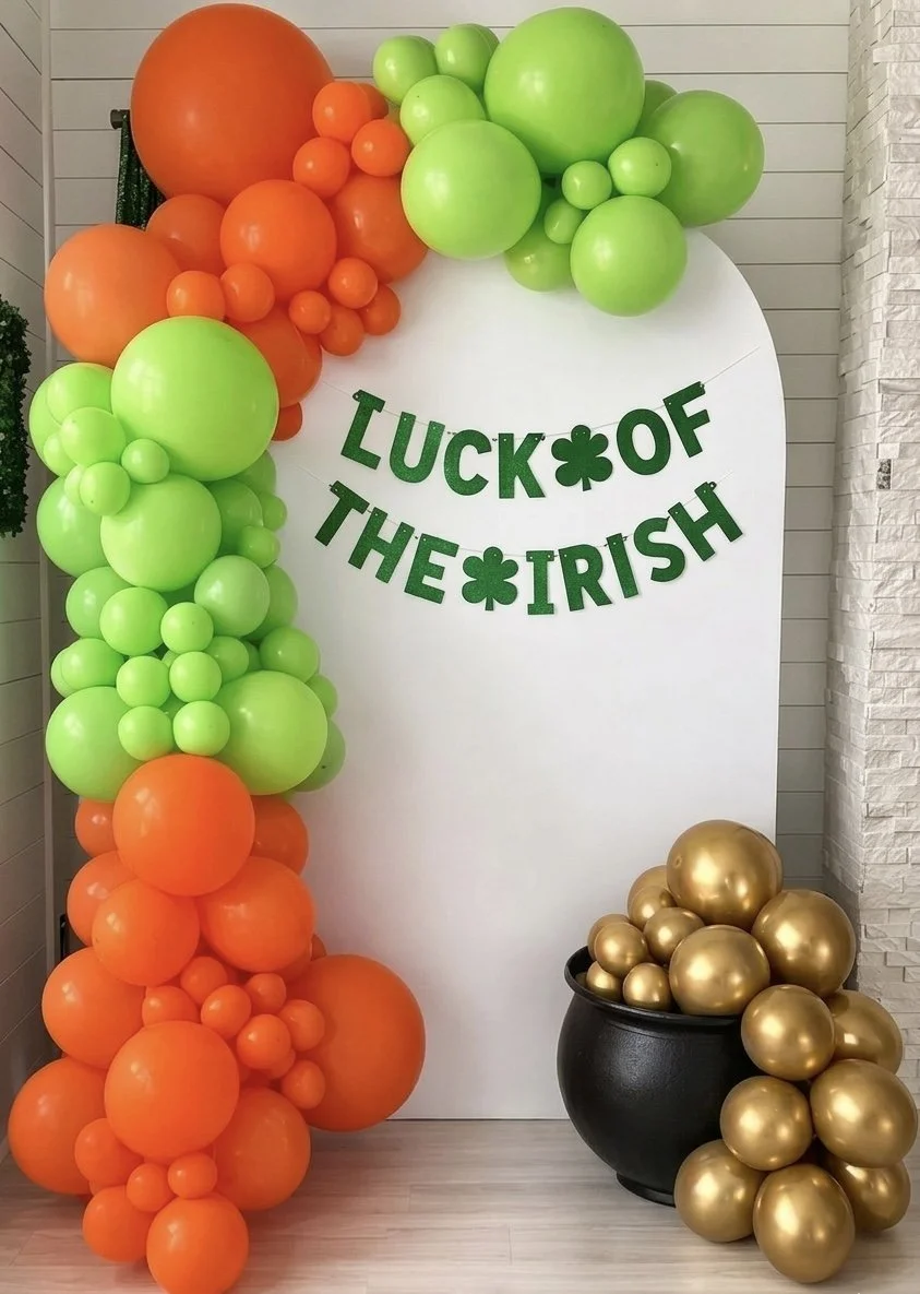 Decorative display of orange, green, and gold balloons with a sign that reads 'Luck of the Irish' and a pot filled with gold balloons, celebrating Irish luck and St. Patrick's Day.