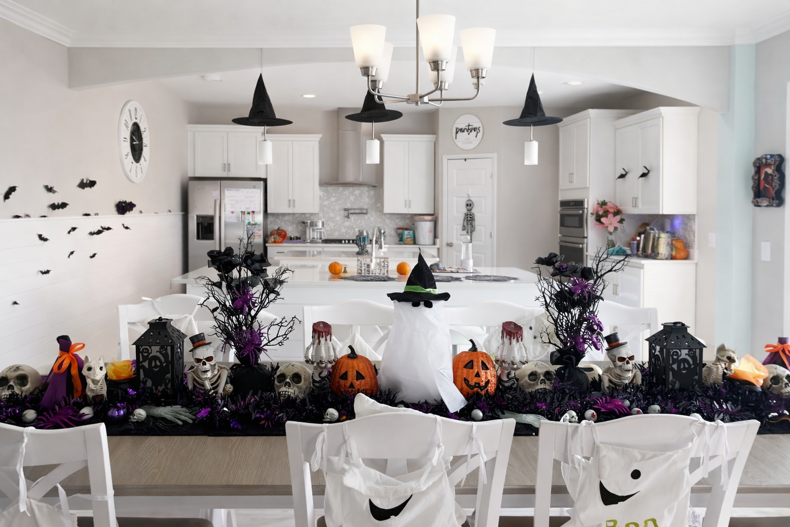 Halloween-themed dining table decoration with a white ghost figure wearing a black witch hat, surrounded by skulls, pumpkins, black lanterns, and purple and black accents, set in a modern kitchen.