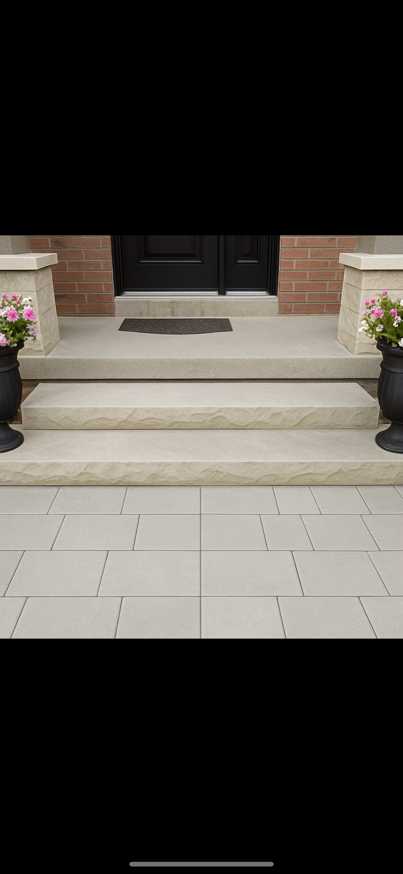 Concrete front steps leading to a black door, flanked by brick columns with flower pots containing pink and white flowers.