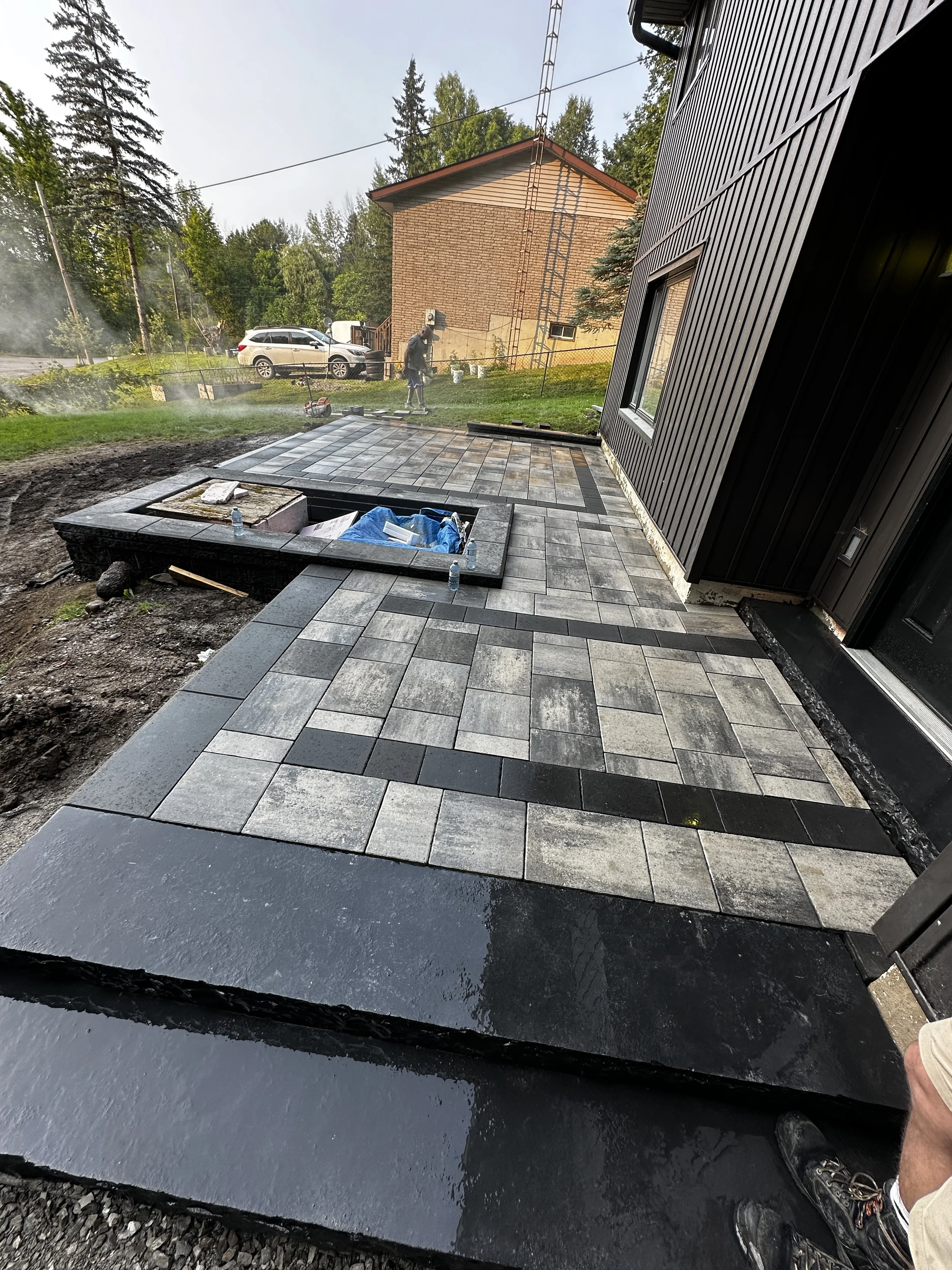 paving stones on a newly paved patio area outside a black building. 