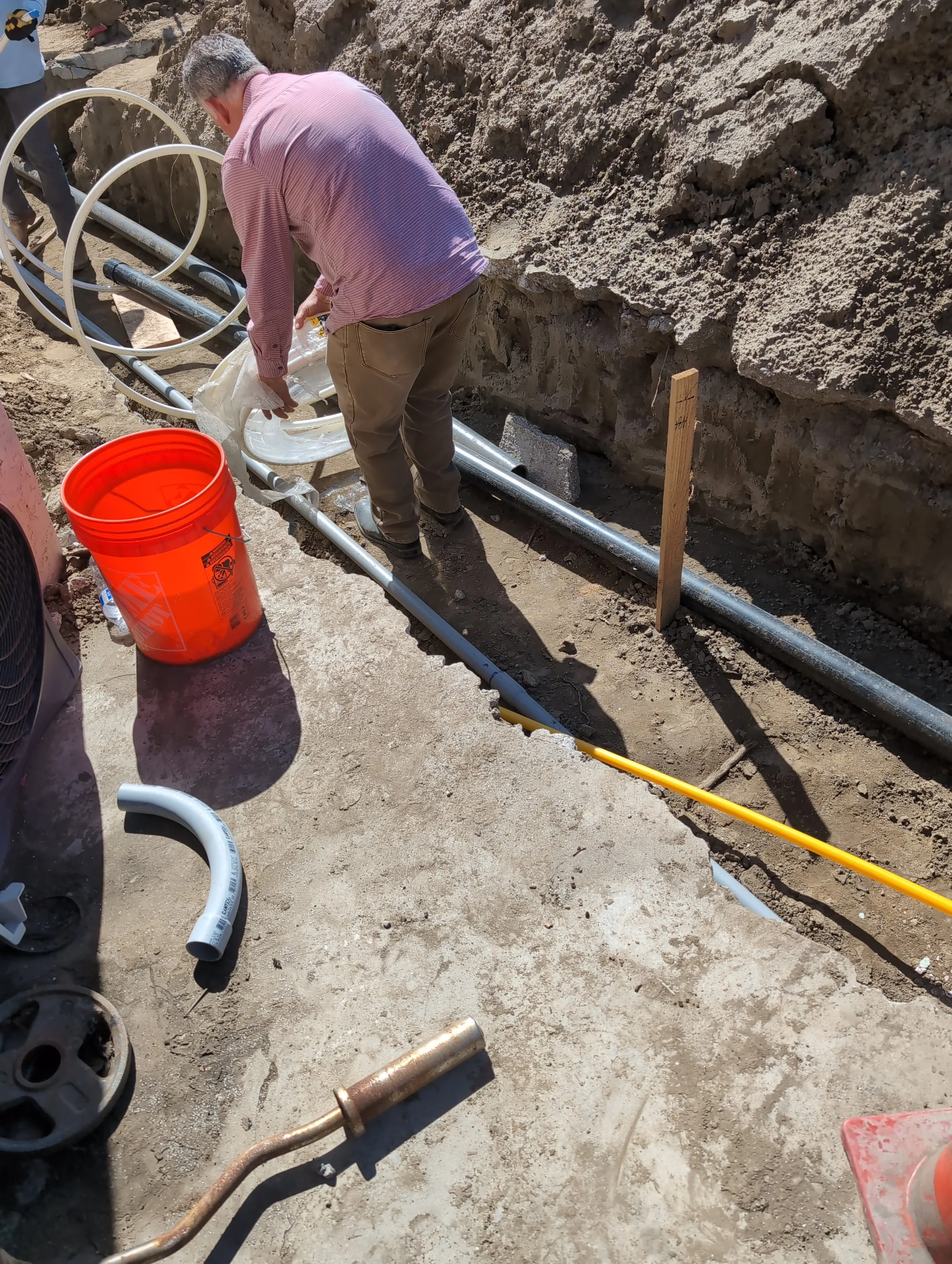 Man working with plumbing pipes on a construction site.