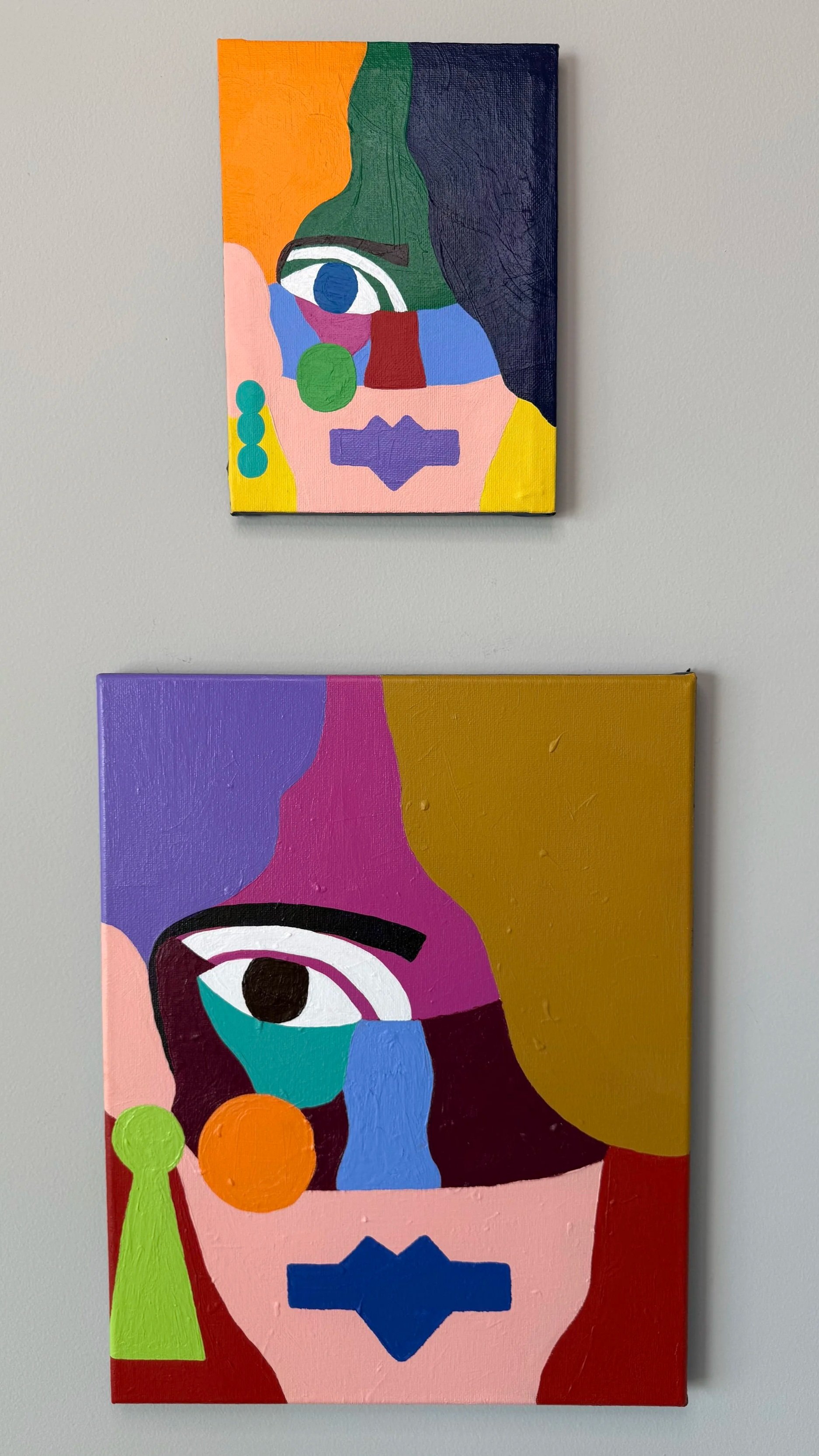 Abstract colorful paintings featuring stylized human faces with large eyes, using vibrant colors like blue, pink, yellow, green, and purple.