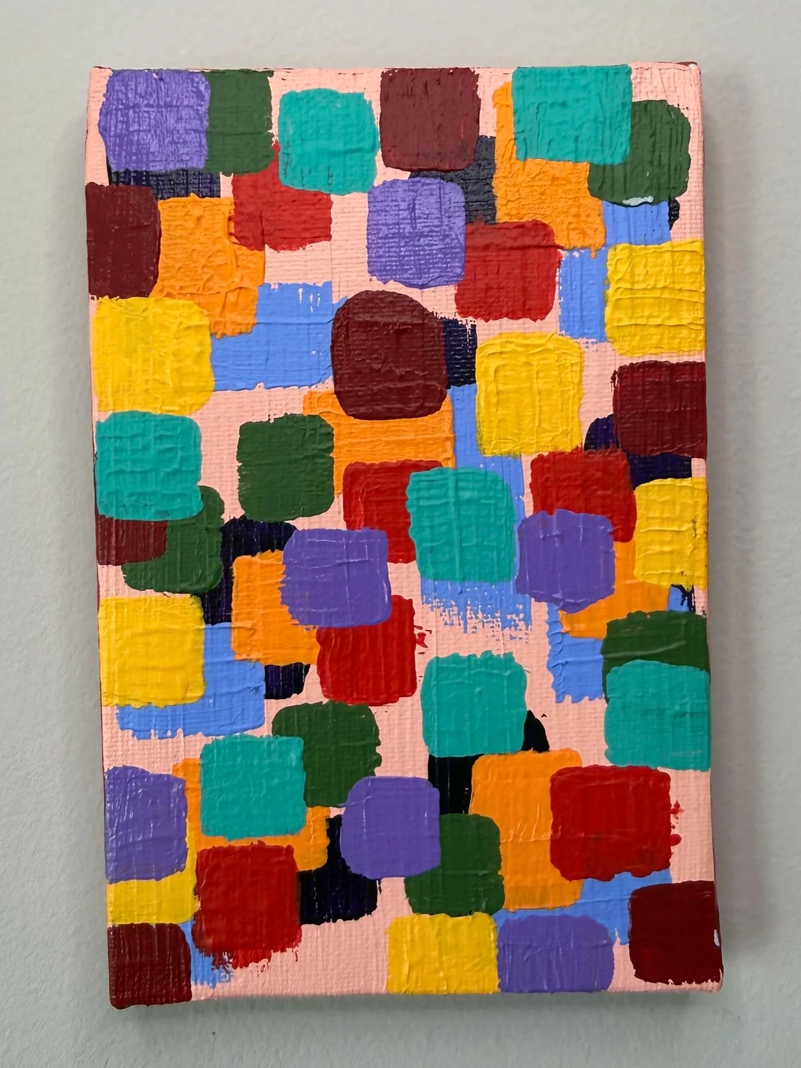 A colorful abstract painting with squares and rectangles of various colors on a pink background.