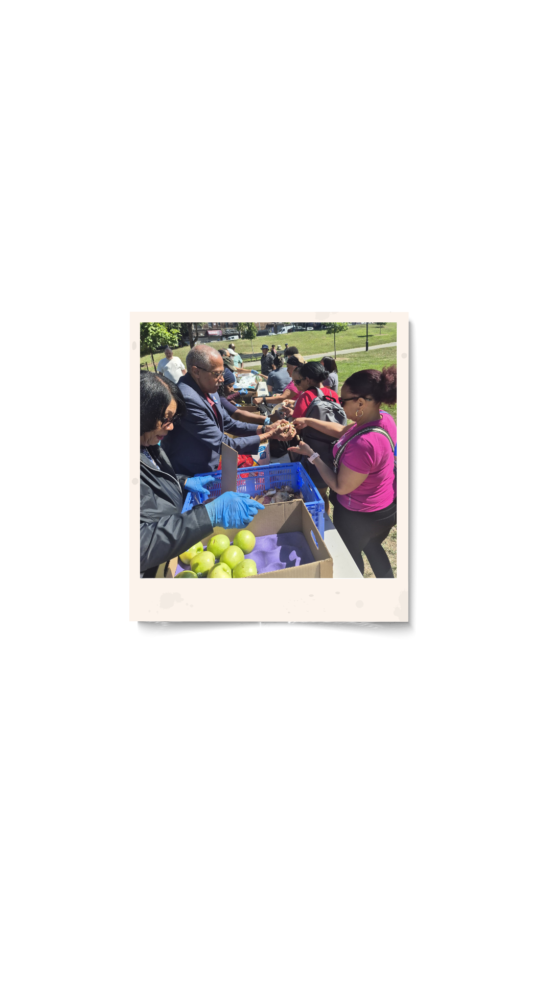 People at an outdoor food distribution event, handing out food to community members.