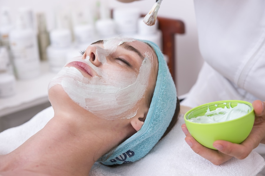 A woman receives a facial treatment with a white cream mask applied to her face at a spa or salon.