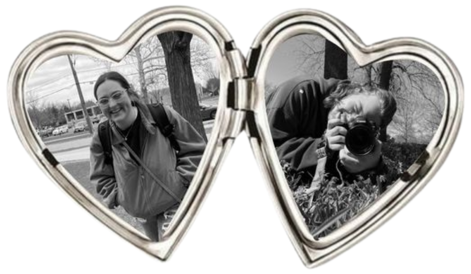 A silver heart-shaped mirror with two reflective surfaces. The left side reflects a woman smiling, wearing glasses, a jacket, and carrying a backpack outdoors with trees and cars in the background. The right side reflects a man holding a camera, crouched among leaves and plants outdoors, with trees and a cloudy sky in the background.
