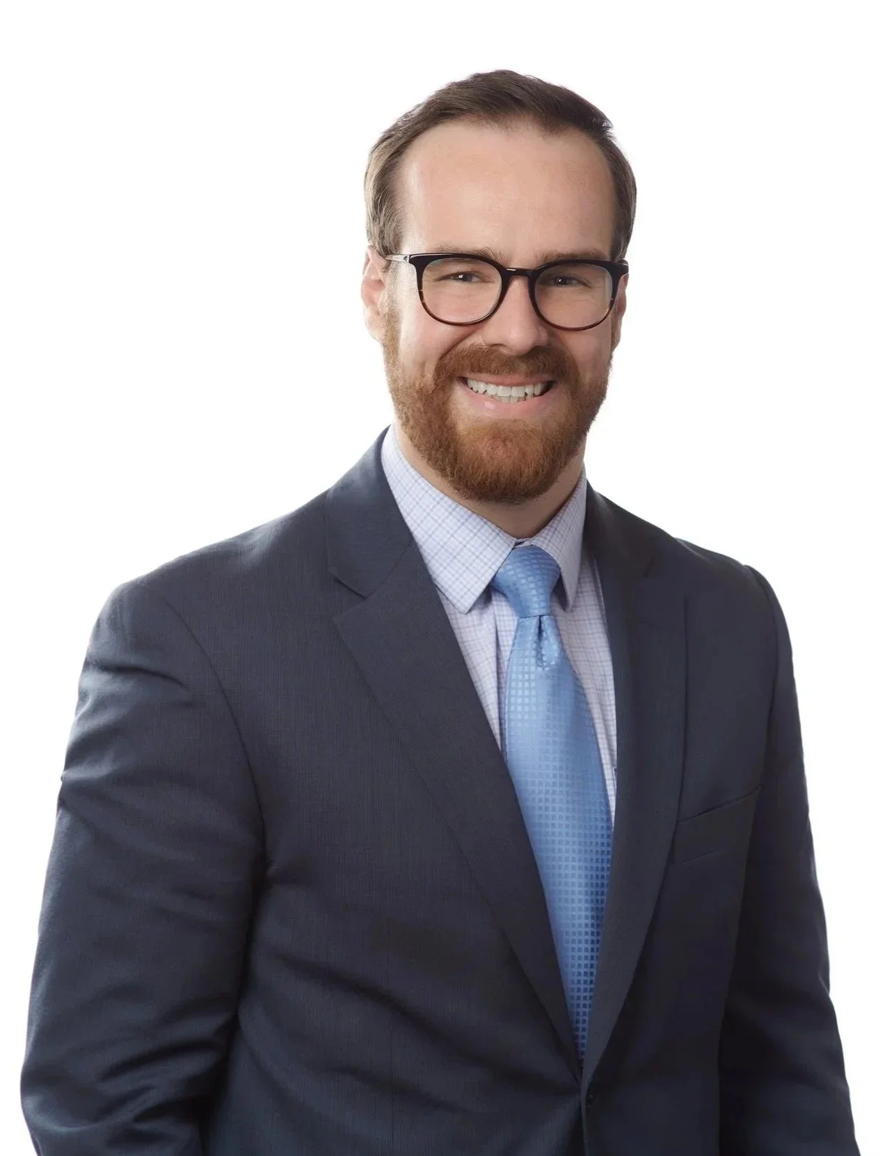A man in a business suit with glasses, a beard, and a friendly smile, wearing a blue tie and a light-colored shirt, against a white background.