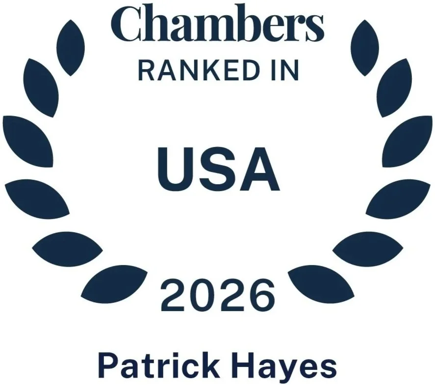 A graphic badge with navy laurel leaves surrounding the text "Chambers RANKED IN USA 2026 Patrick Hayes" in navy font.