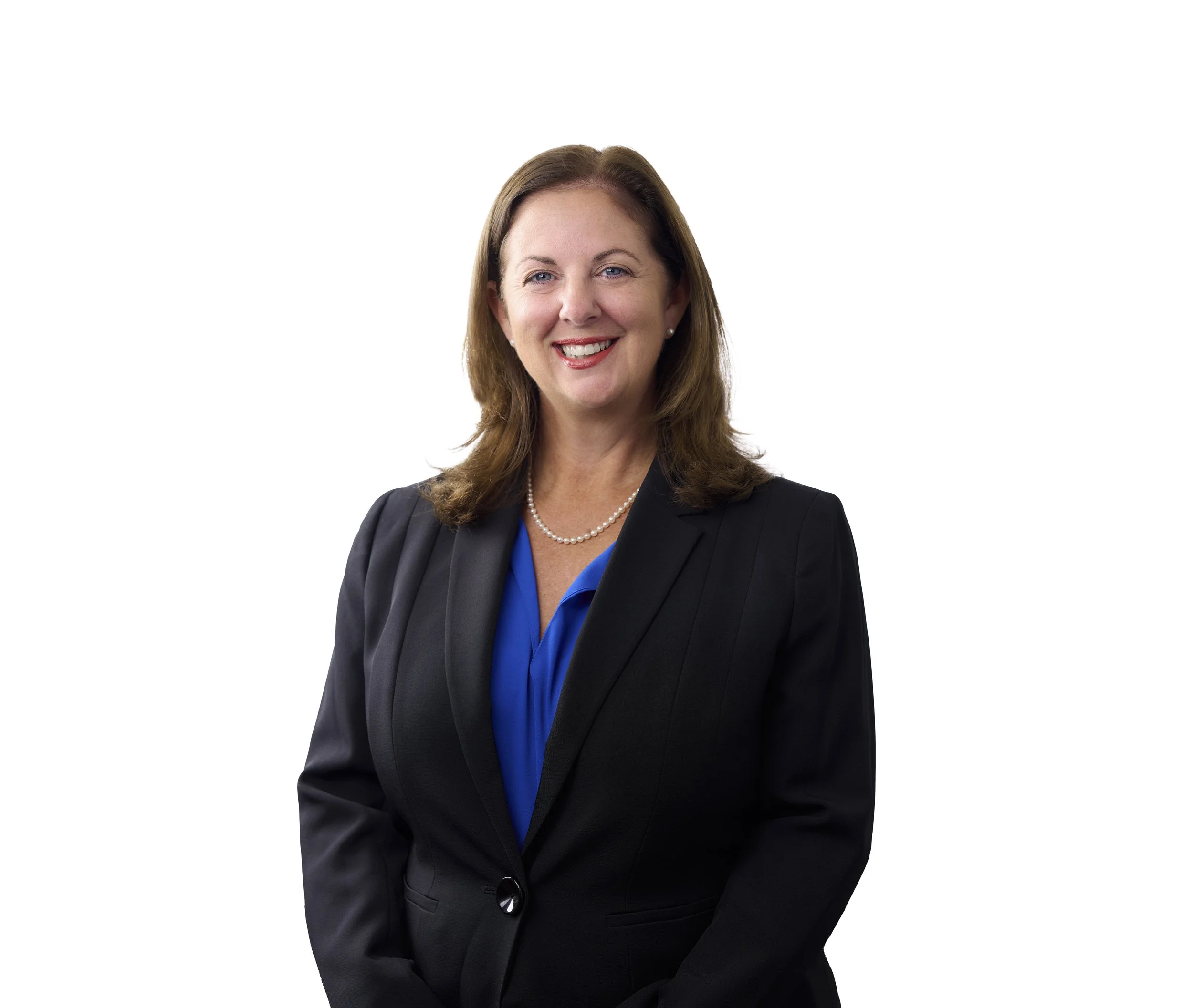 A professional woman with shoulder-length brown hair, wearing a dark blazer, blue blouse, pearl necklace, and earrings, smiling against a white background.