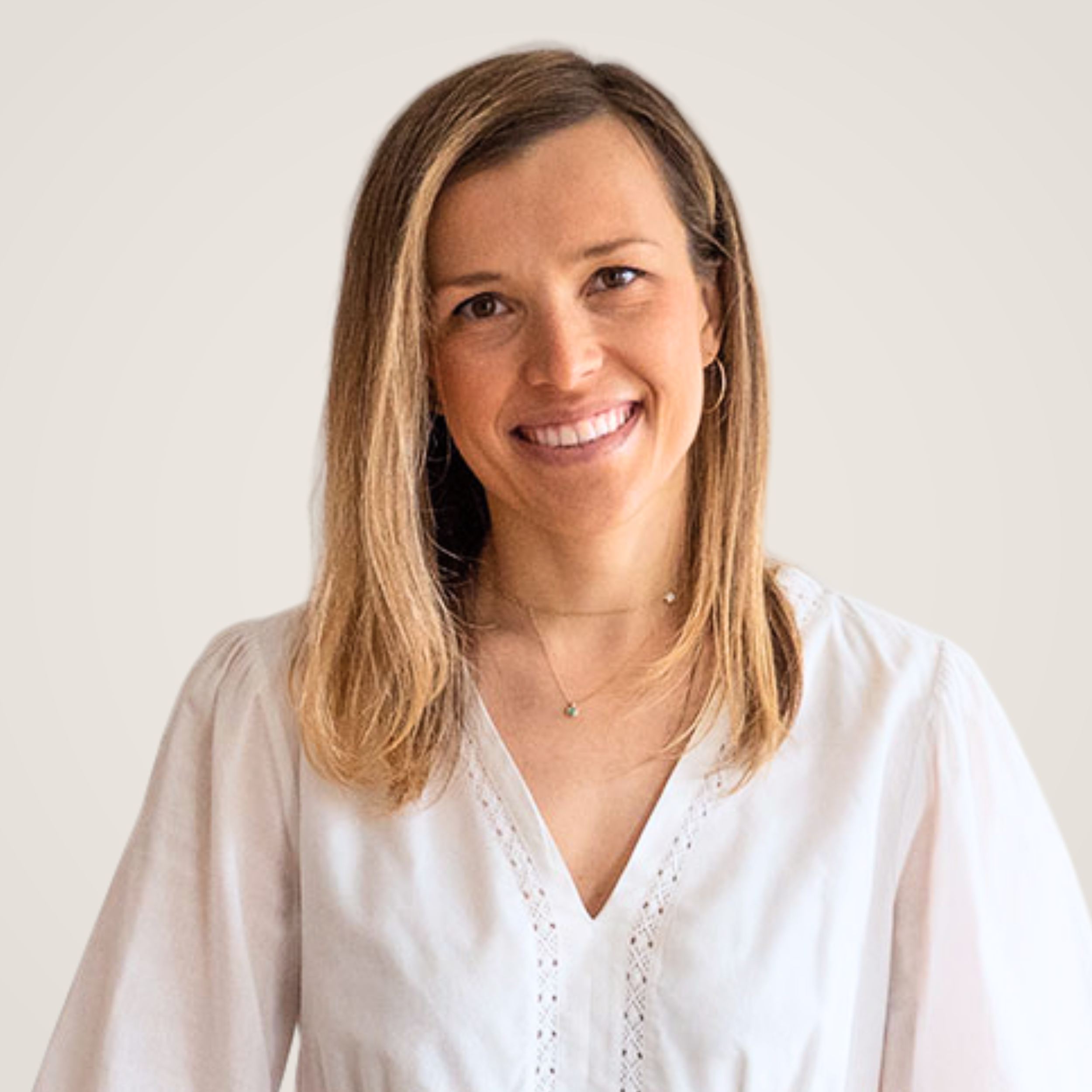 Portrait of a smiling woman with shoulder-length light brown hair wearing a white blouse and jewelry, against a plain background.