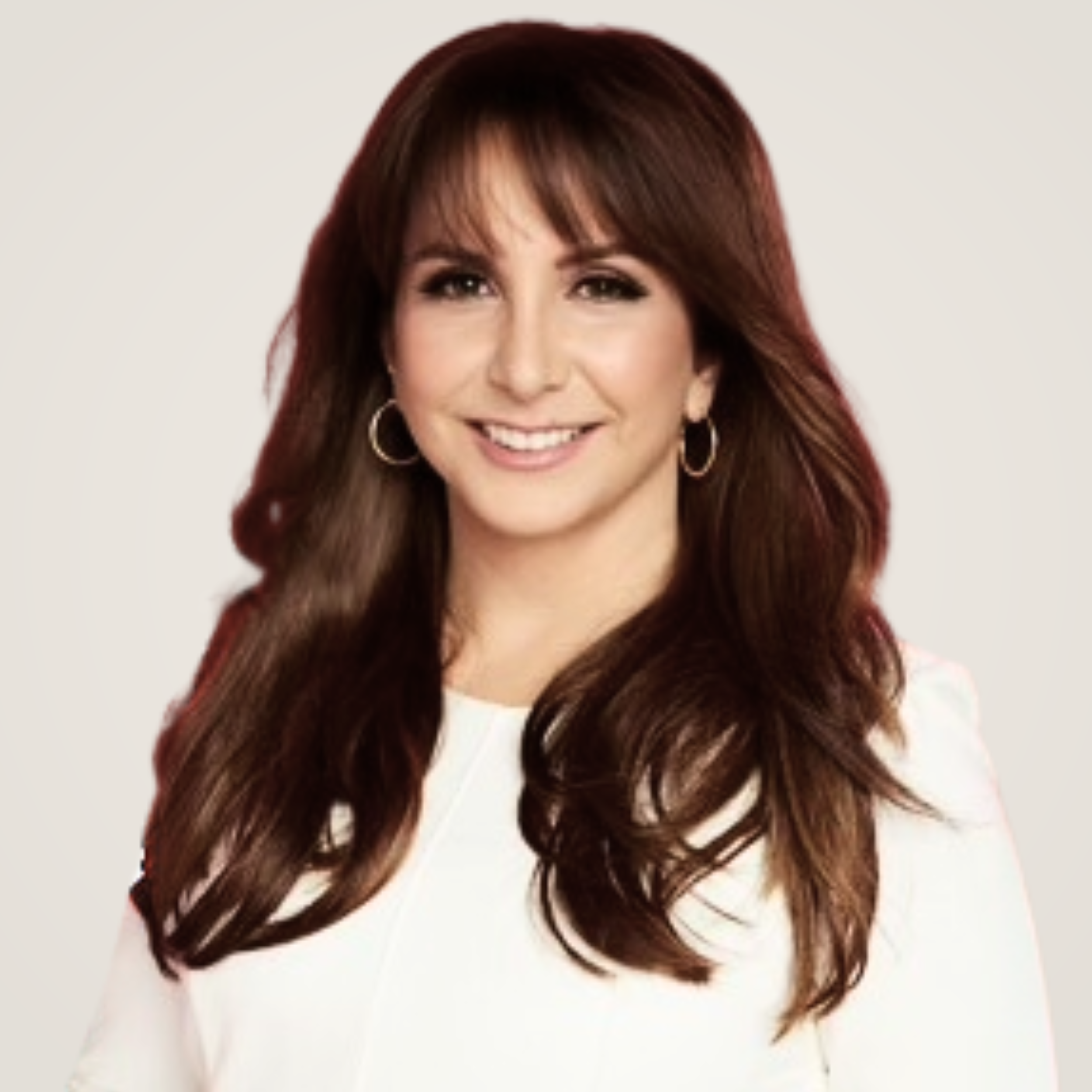 Portrait of a woman with long, wavy brown hair, hoop earrings, and a white top, smiling against a plain background.