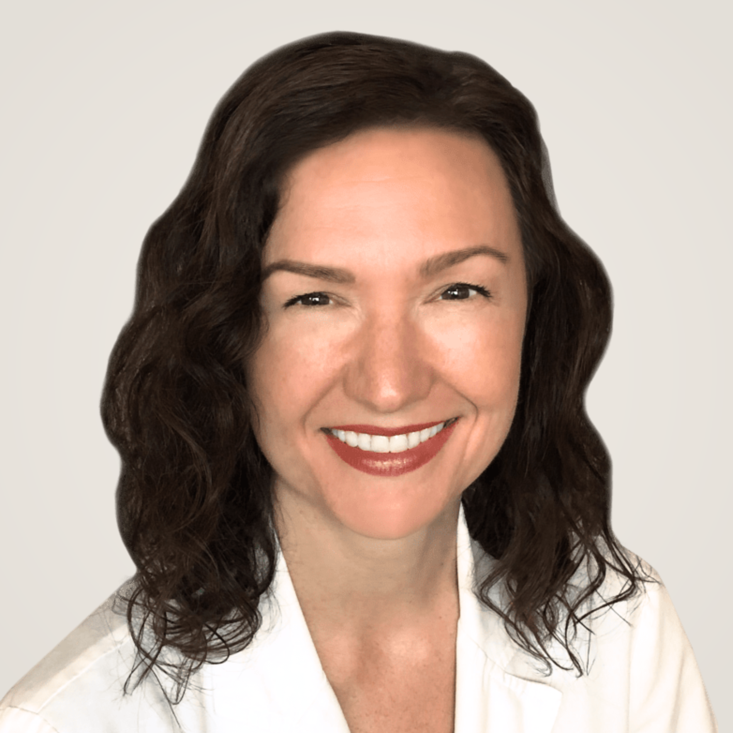 Dr. Allison Siebecker | A woman with wavy brown hair smiling with makeup including lipstick, wearing a white top, against a plain light background.