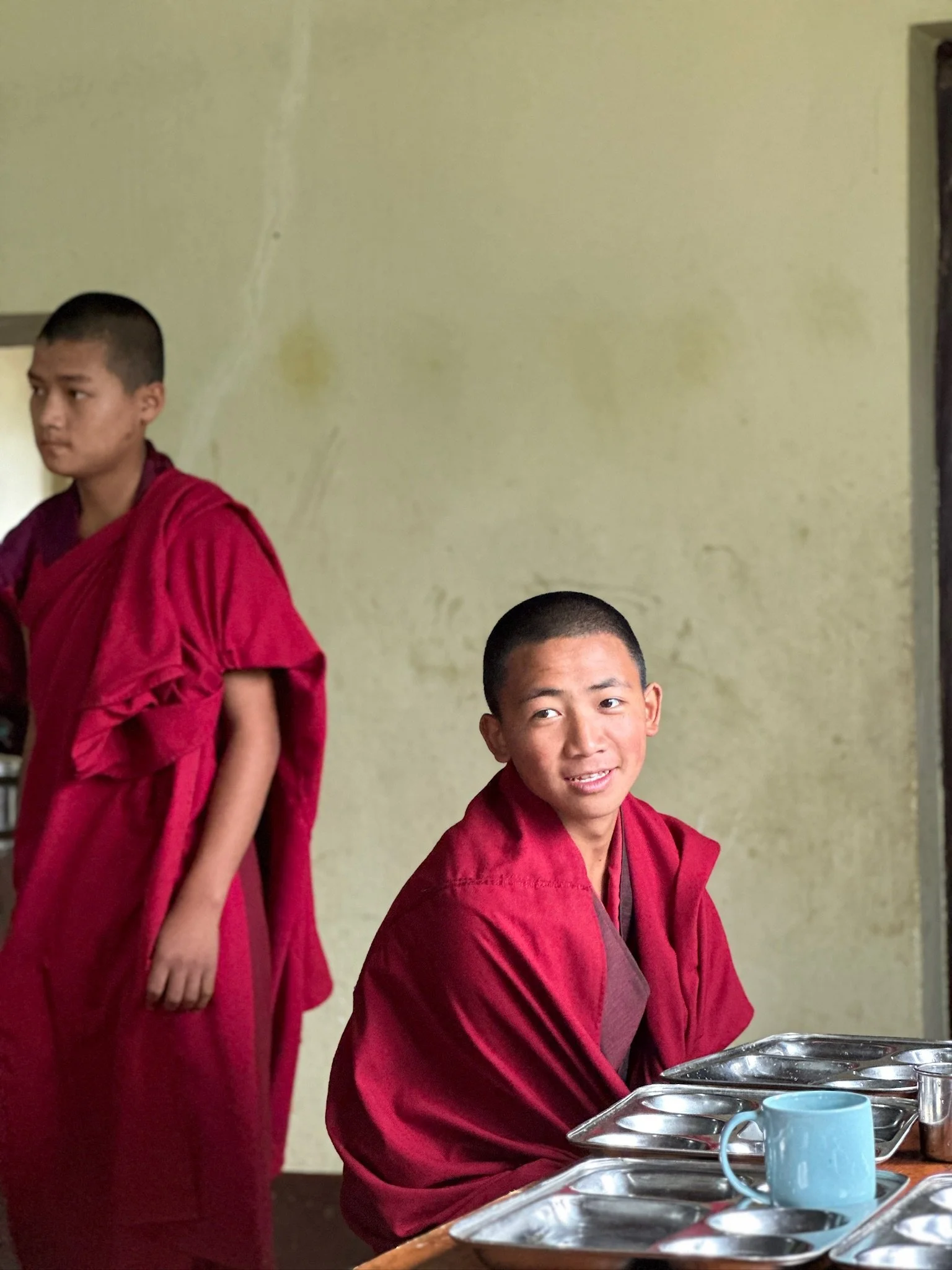 Young monks in red robes during a breakfast experience at a monastery in Bhutan.