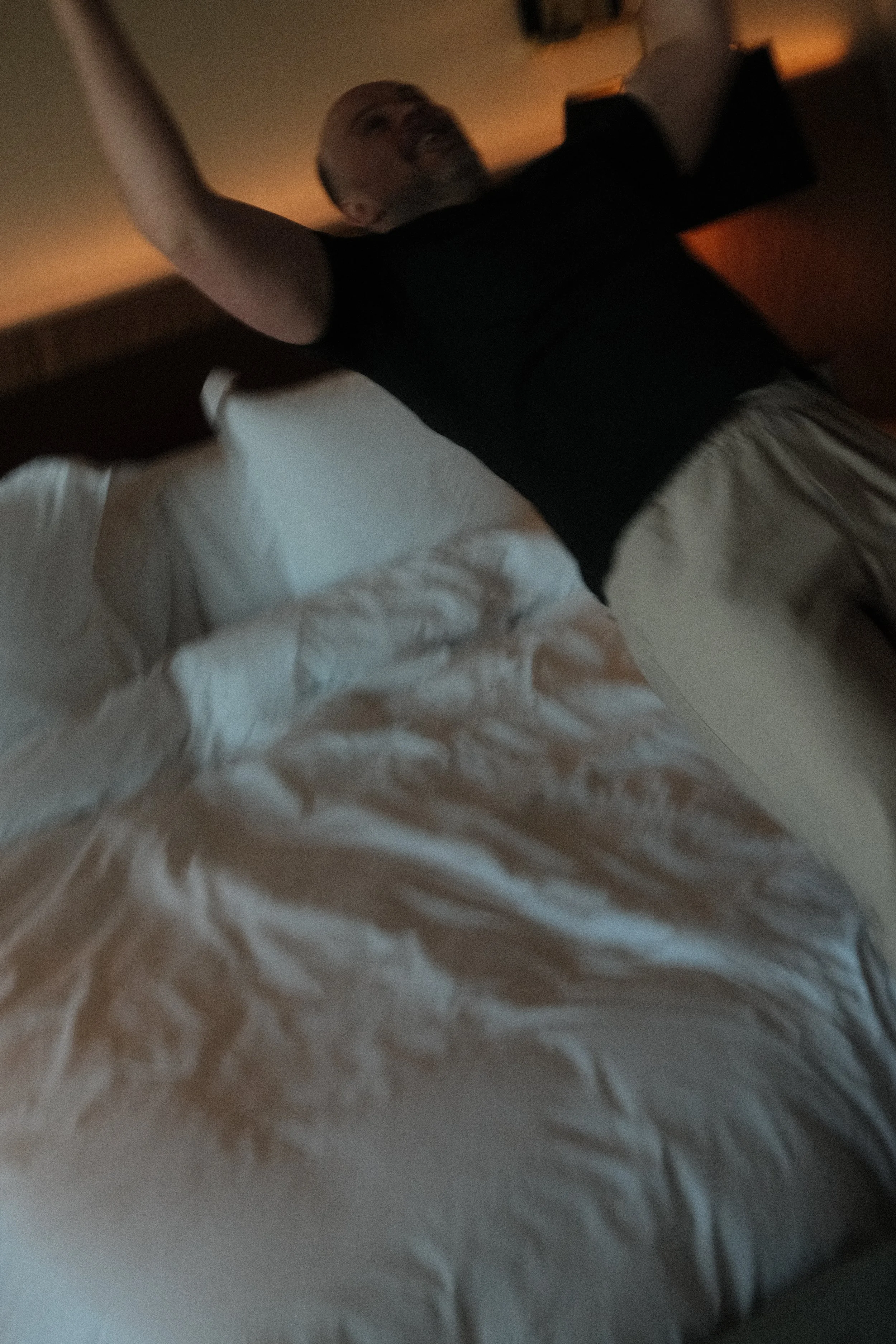 Matt relaxing beneath white bedding in a softly lit room at Four Seasons Hotel Ritz Lisbon.