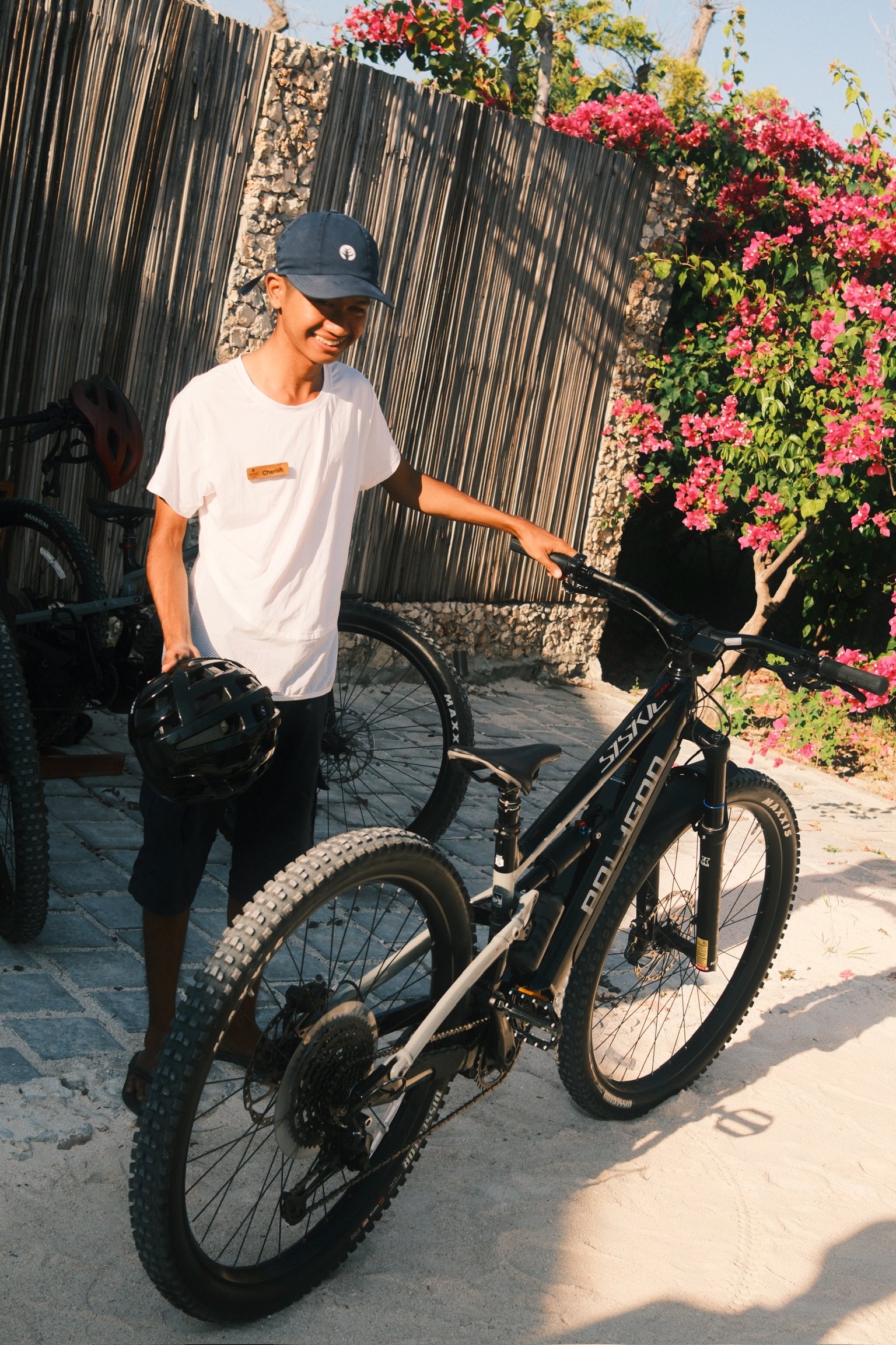 A NIHI Rote host holding a helmet beside a mountain bike.