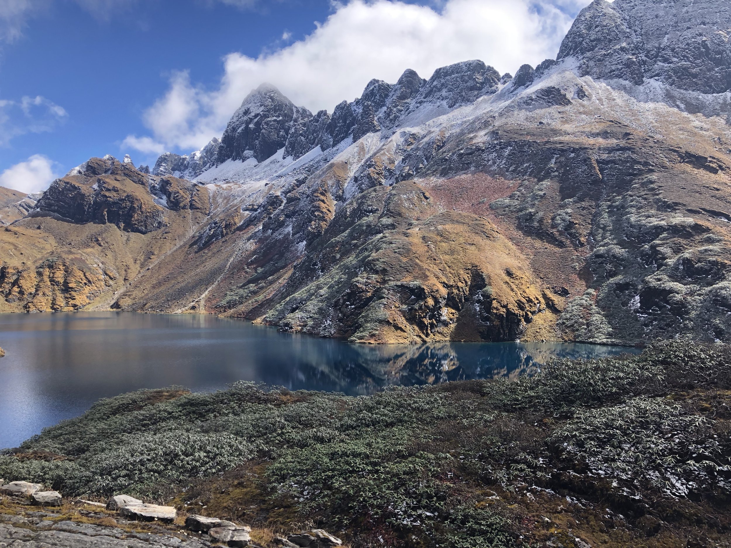 Snow-dusted mountains reflected in a glacial lake on the Snowman Trek in Bhutan.