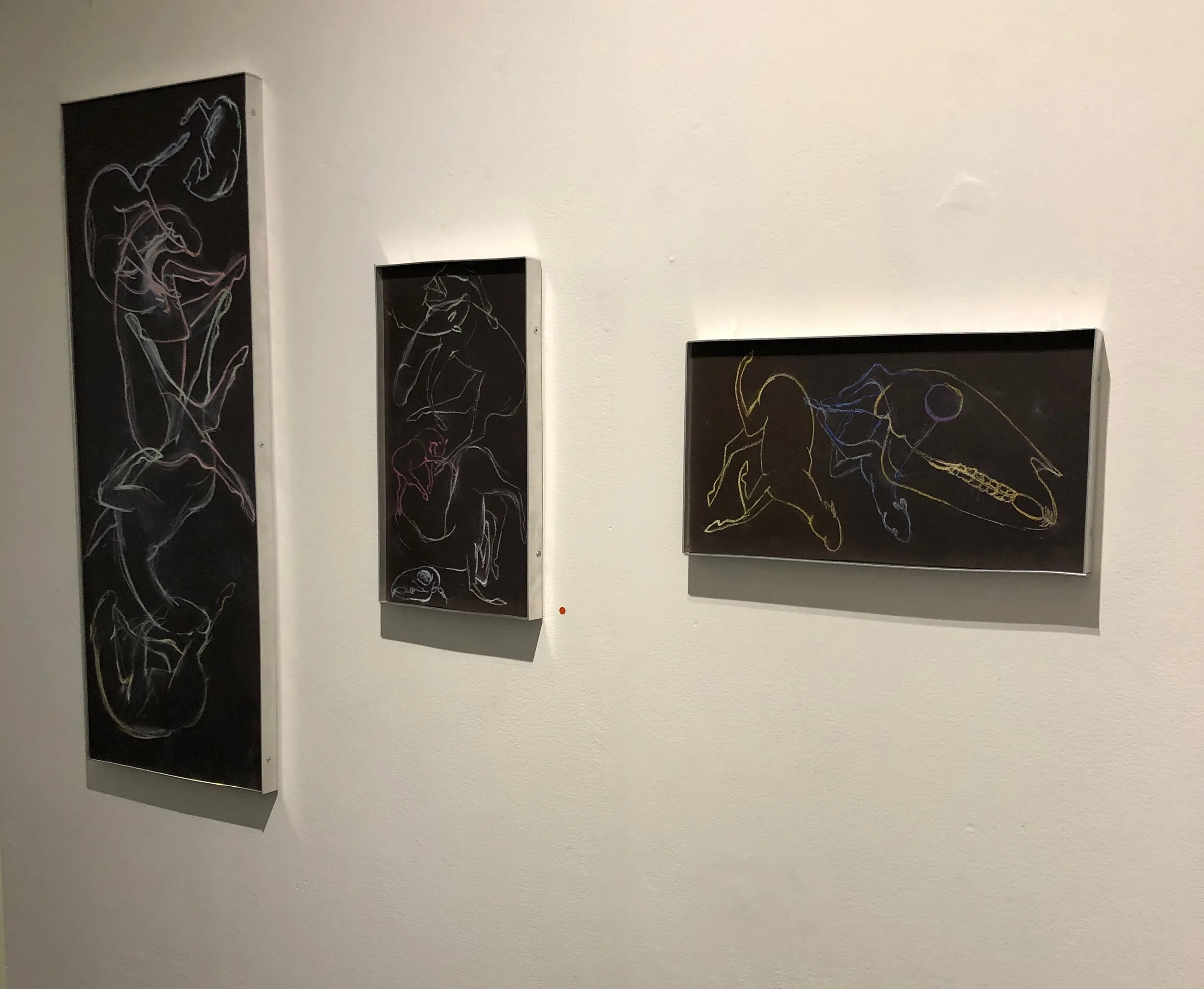 Three framed chalkboard-style artworks depicting abstract animal poses on a white gallery wall.