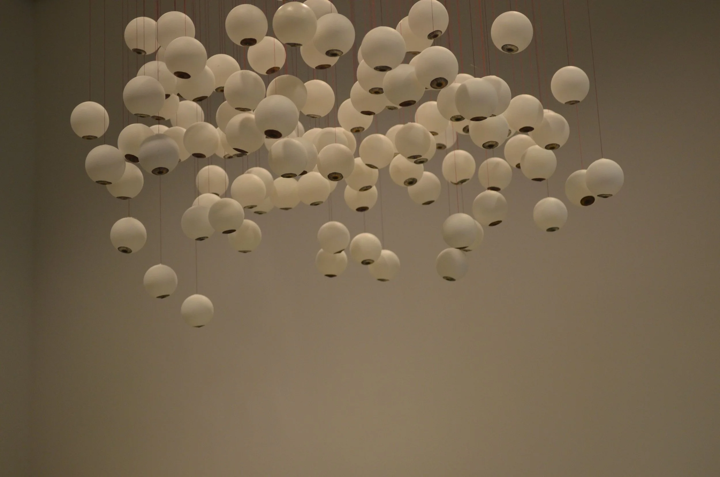 A large modern chandelier with numerous white spherical pendant lights hanging at different lengths from the ceiling.