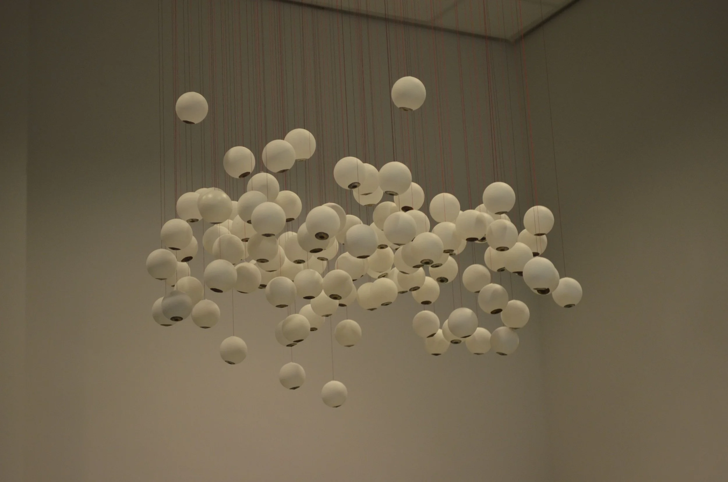 A large modern chandelier with multiple white round globes suspended from the ceiling.