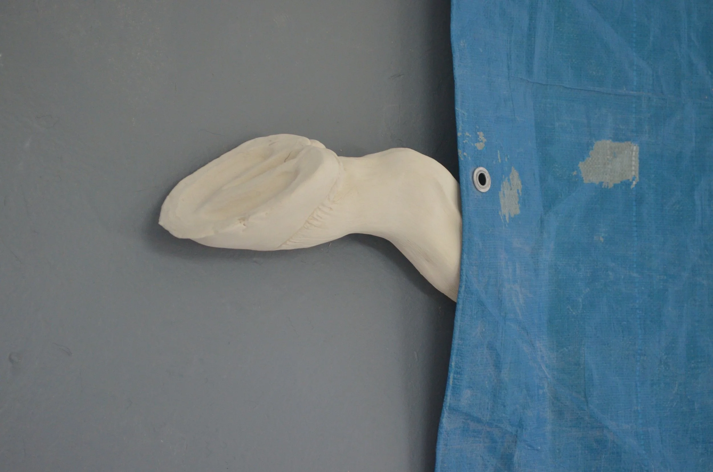 A white anatomical model of a human brain embedded in a blue fabric, placed against a gray wall.