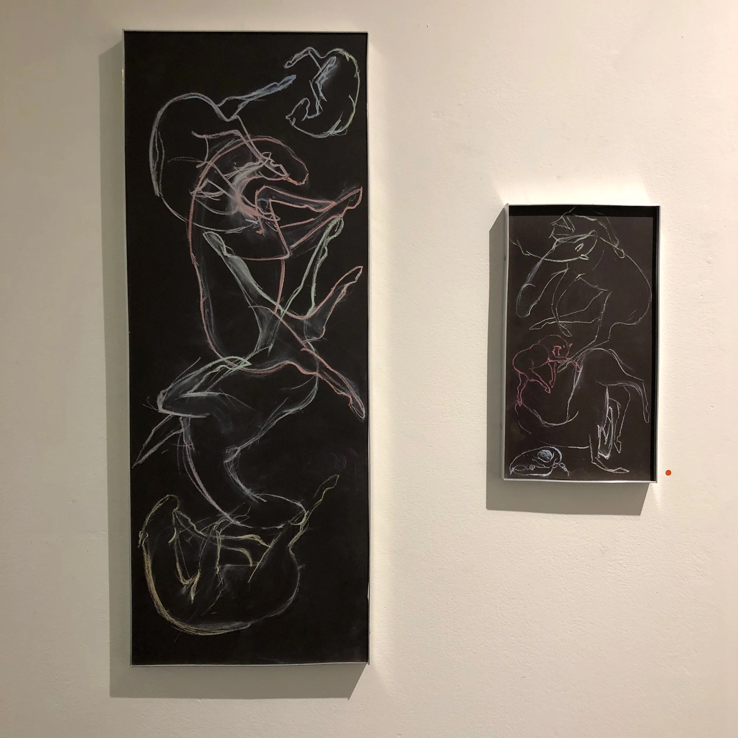 Two framed abstract line drawings of human figures on a white gallery wall, one large vertical on the left and a smaller rectangular on the right.