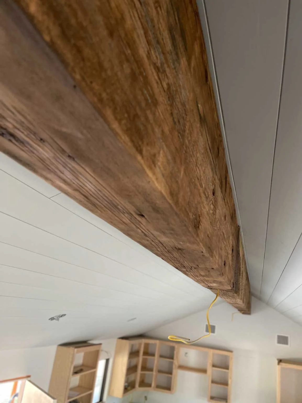 Close-up of a wooden cabinet or countertop with an electrical wire hanging underneath.