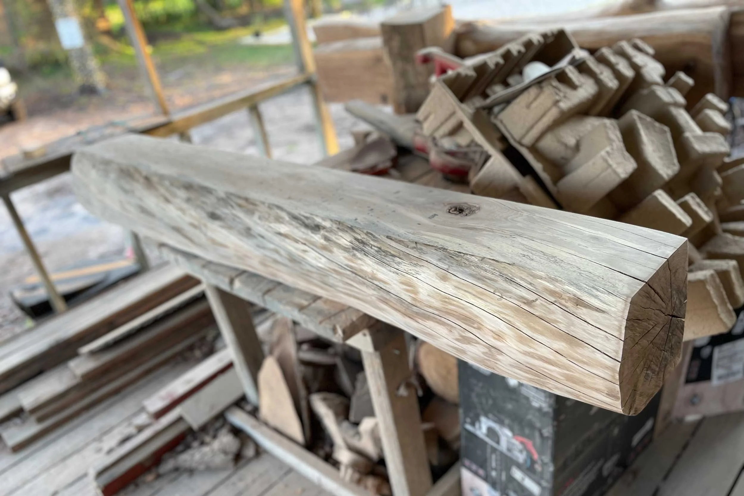 Close-up of a shaped, unfinished piece of wood on a work table in a woodworking shop.