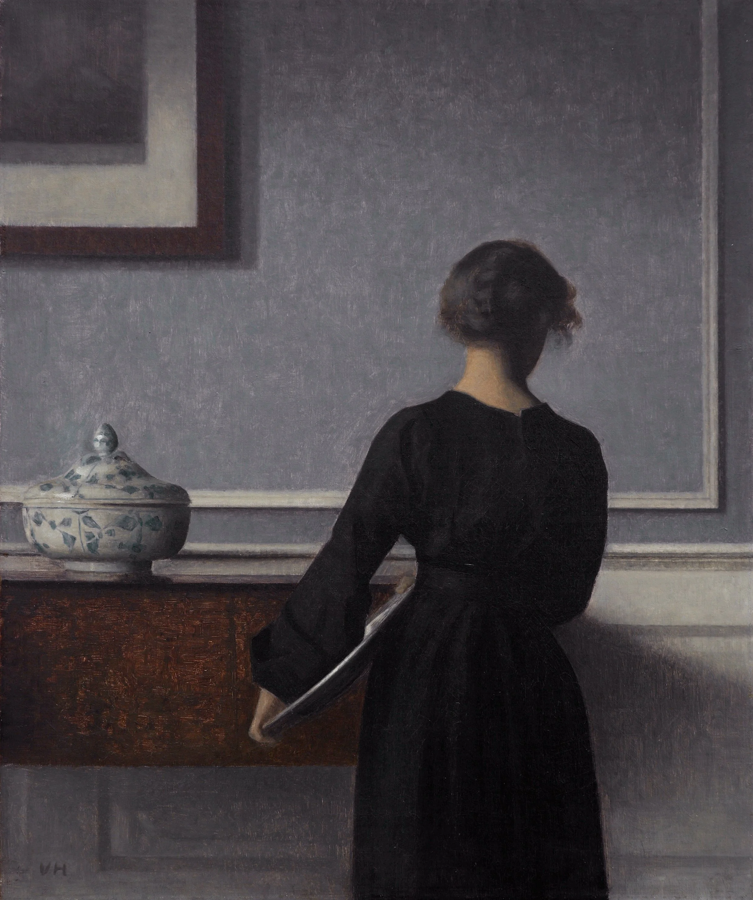 Vilhelm Hammershøi's painting "Interior with Young Woman from Behind," depicting a woman in a long black dress standing with her back turned, beside a sideboard with a porcelain tureen.
