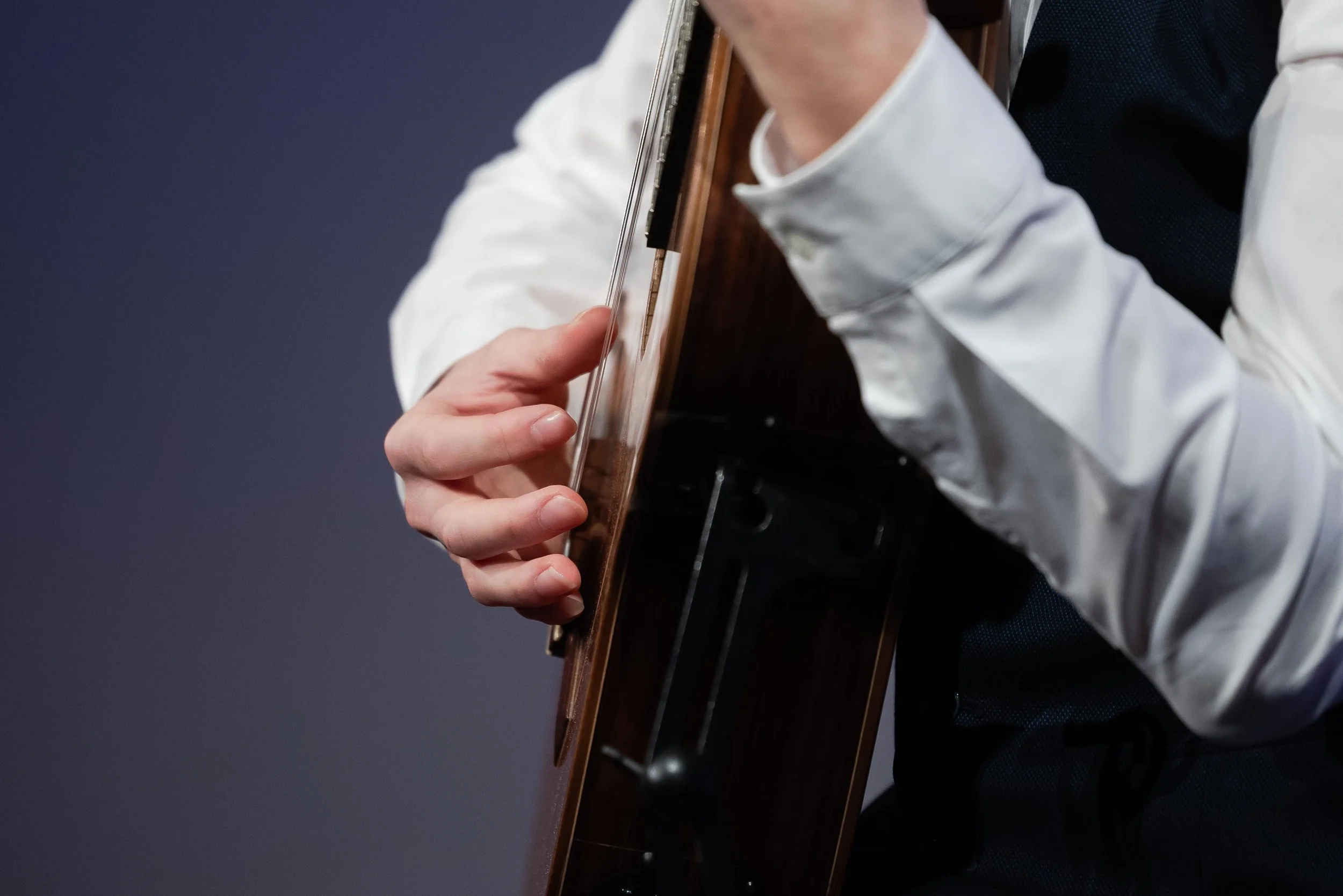 Person playing guitar, focusing on their hand and part of the guitar body.