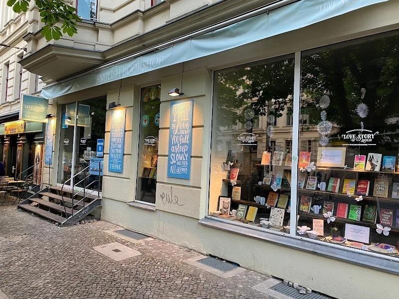Exterior of an English bookstore named Love Story, with display windows showcasing books and decorations, and a staircase leading to the entrance.