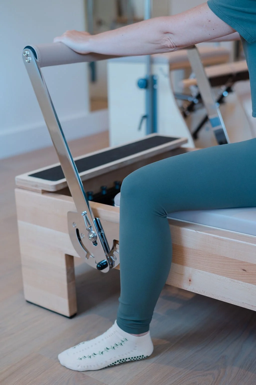 Two women practicing Pilates on reformer machines in a modern studio, performing a leg lift exercise.