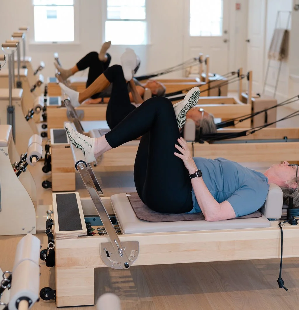Person adjusting a yoga mat on a black exercise mat indoors.