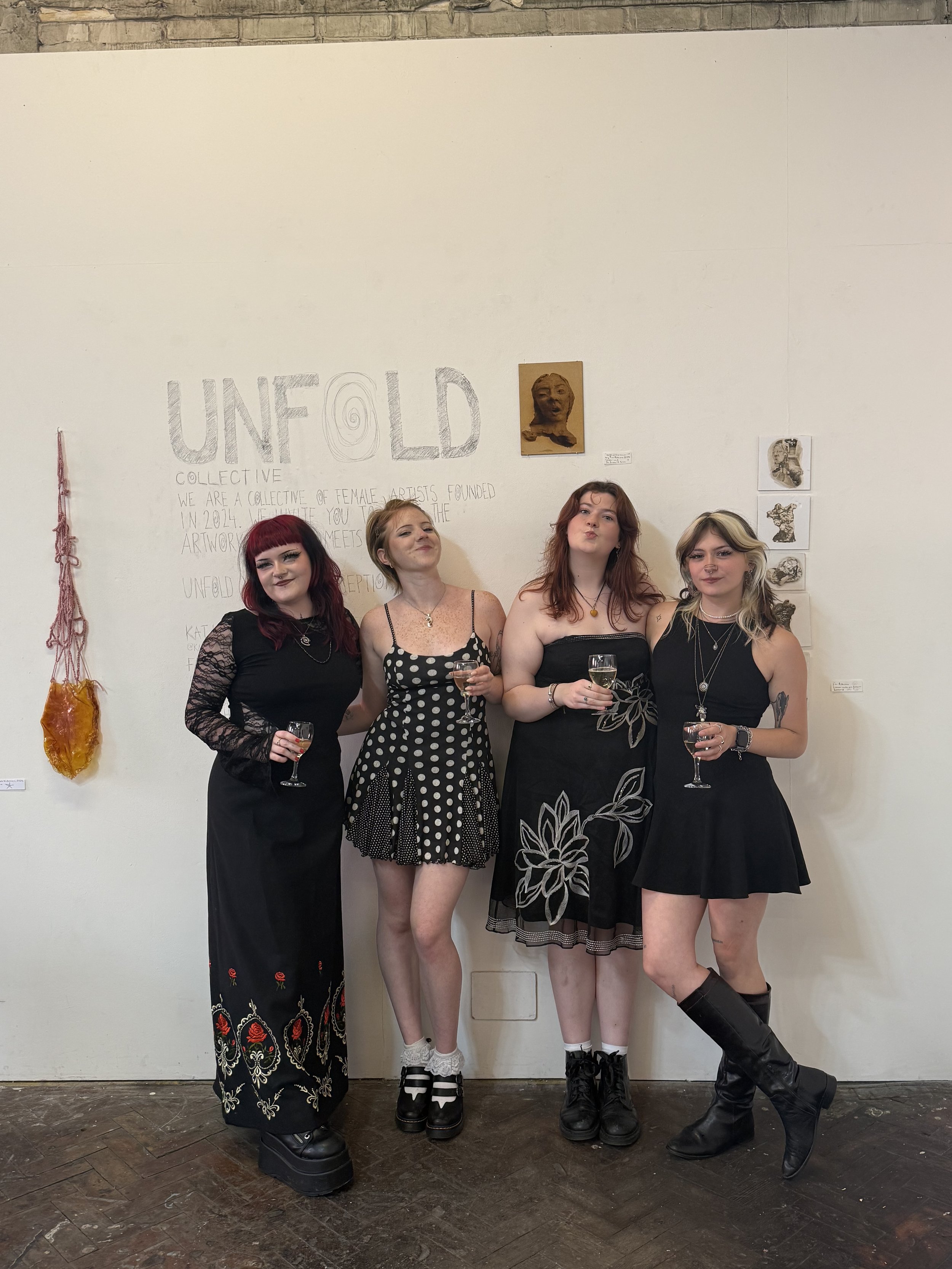 the artist with her all female collective, standing in front of their exhibition title wall.