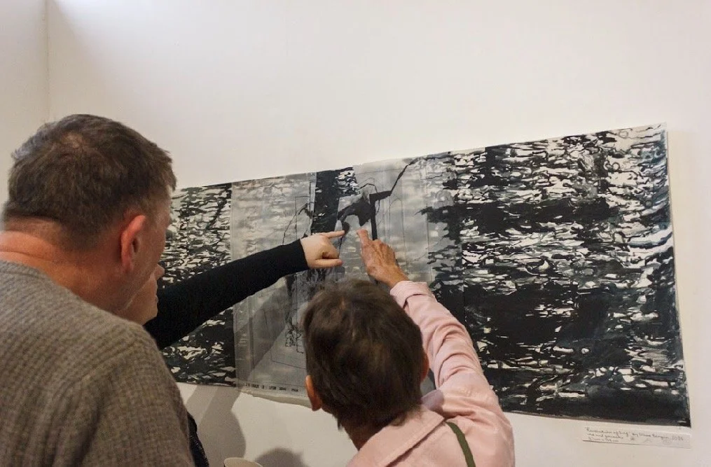 three people inspecting art work by Olive Bergin