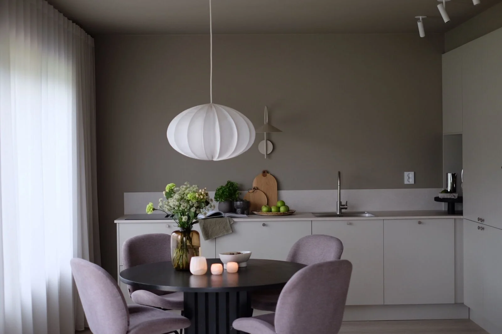 Moderne kjøkken i beige med rundt spisegruppe og lampe over bordet