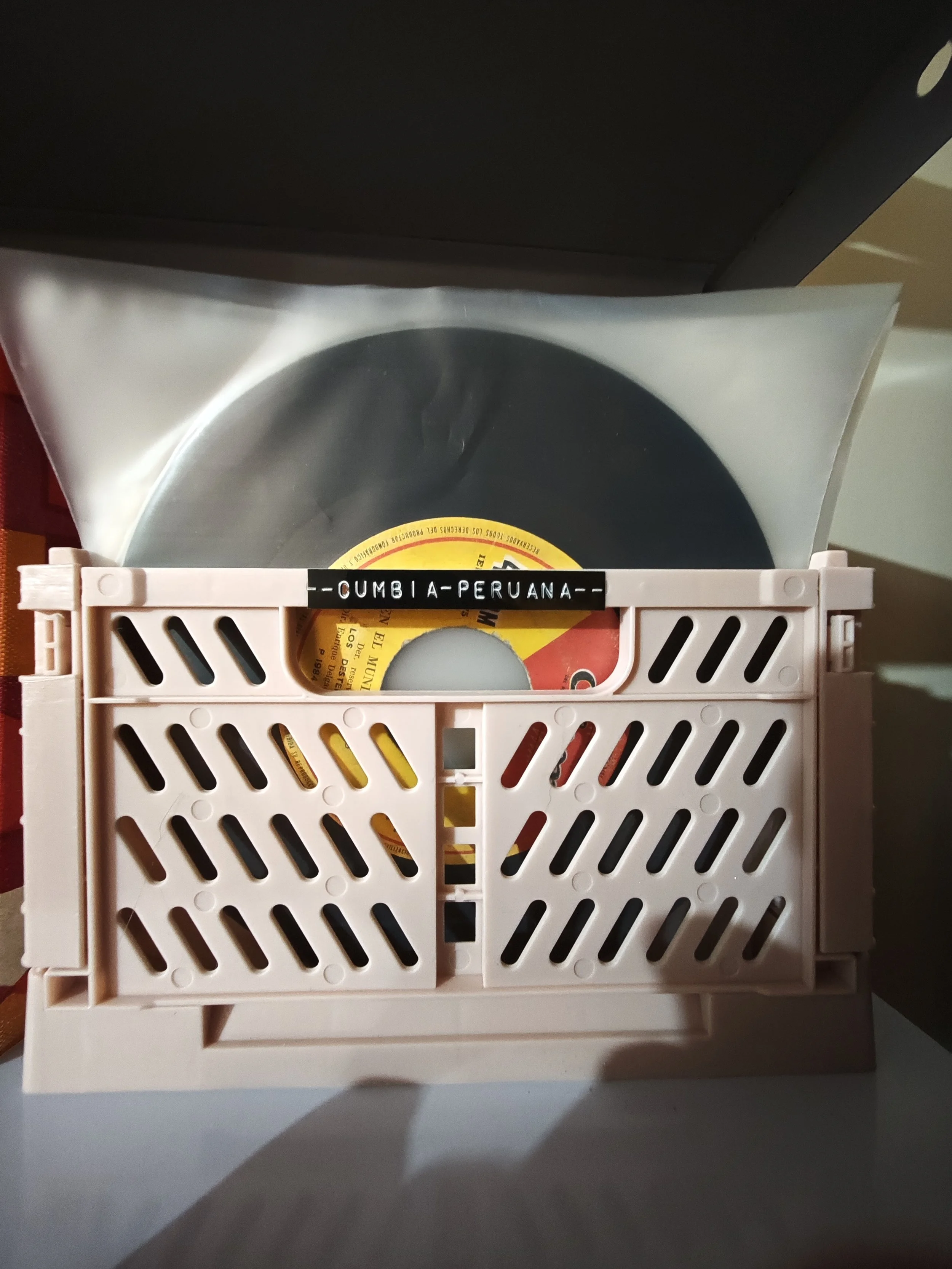 Disco de vinilo en una caja de plástico rosa, etiquetado como 'Cumbia Peruana'.