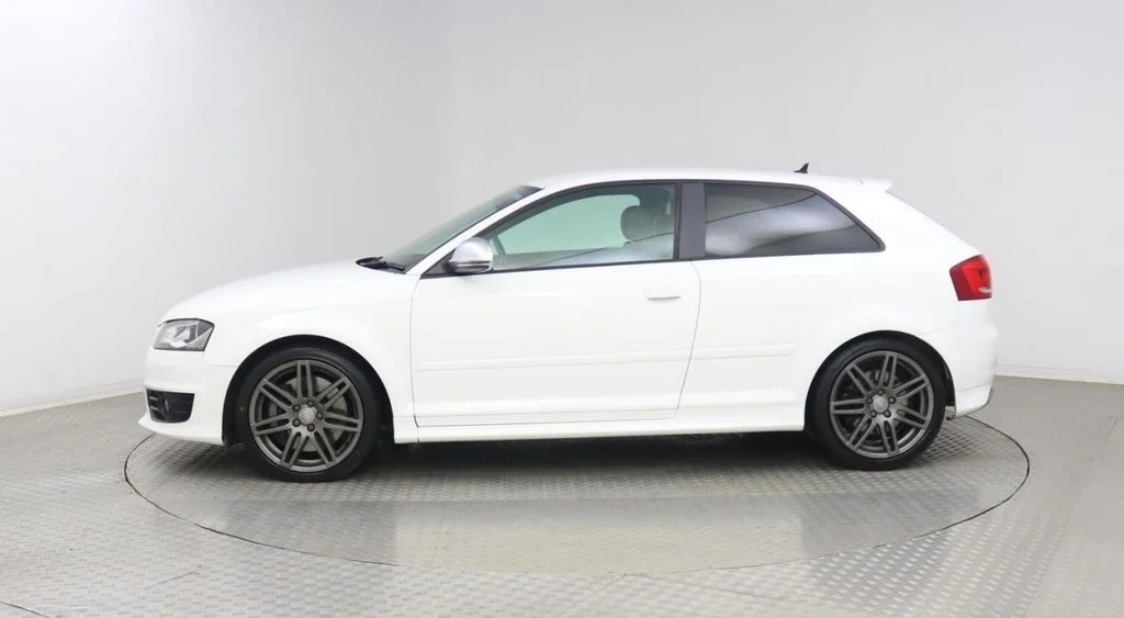 White Audi A3 hatchback car with black rims parked on a turntable in a photography studio.