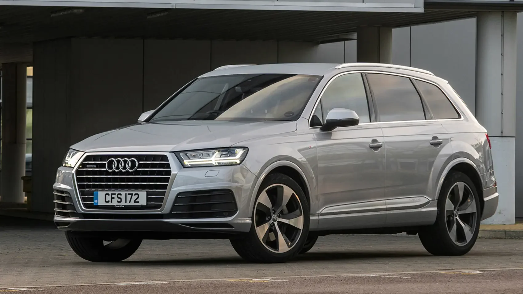 Silver Audi SUV parked under a modern concrete structure.