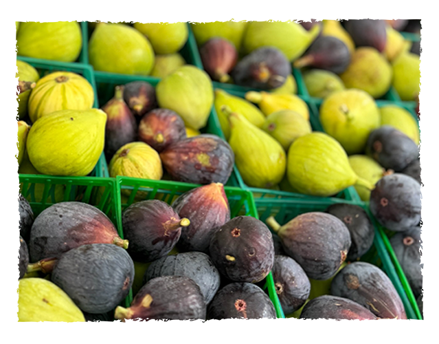 Fresh green and purple figs in green plastic baskets at a market