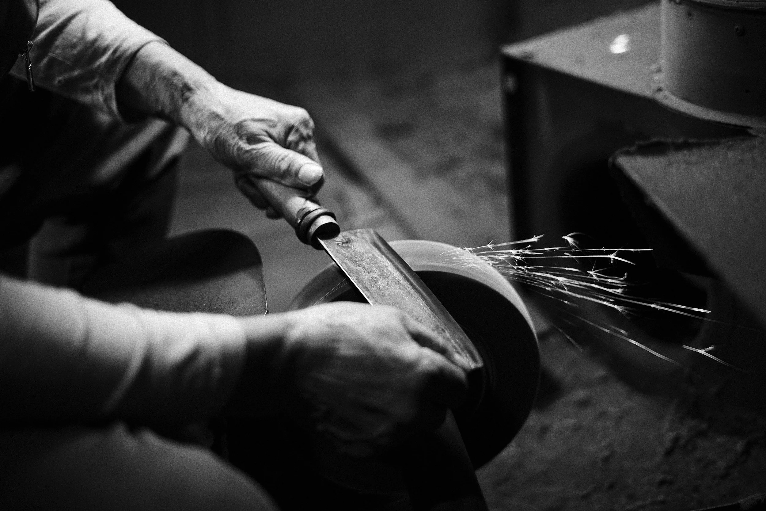 A person grinding a piece of metal with sparks flying.