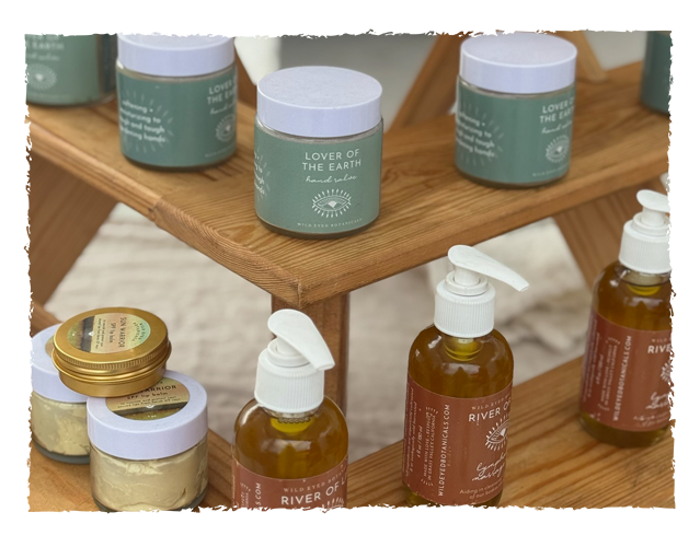 Display of natural skincare products including jars labeled 'Lover of the Earth' and amber bottles with pump dispensers on a wooden stand.