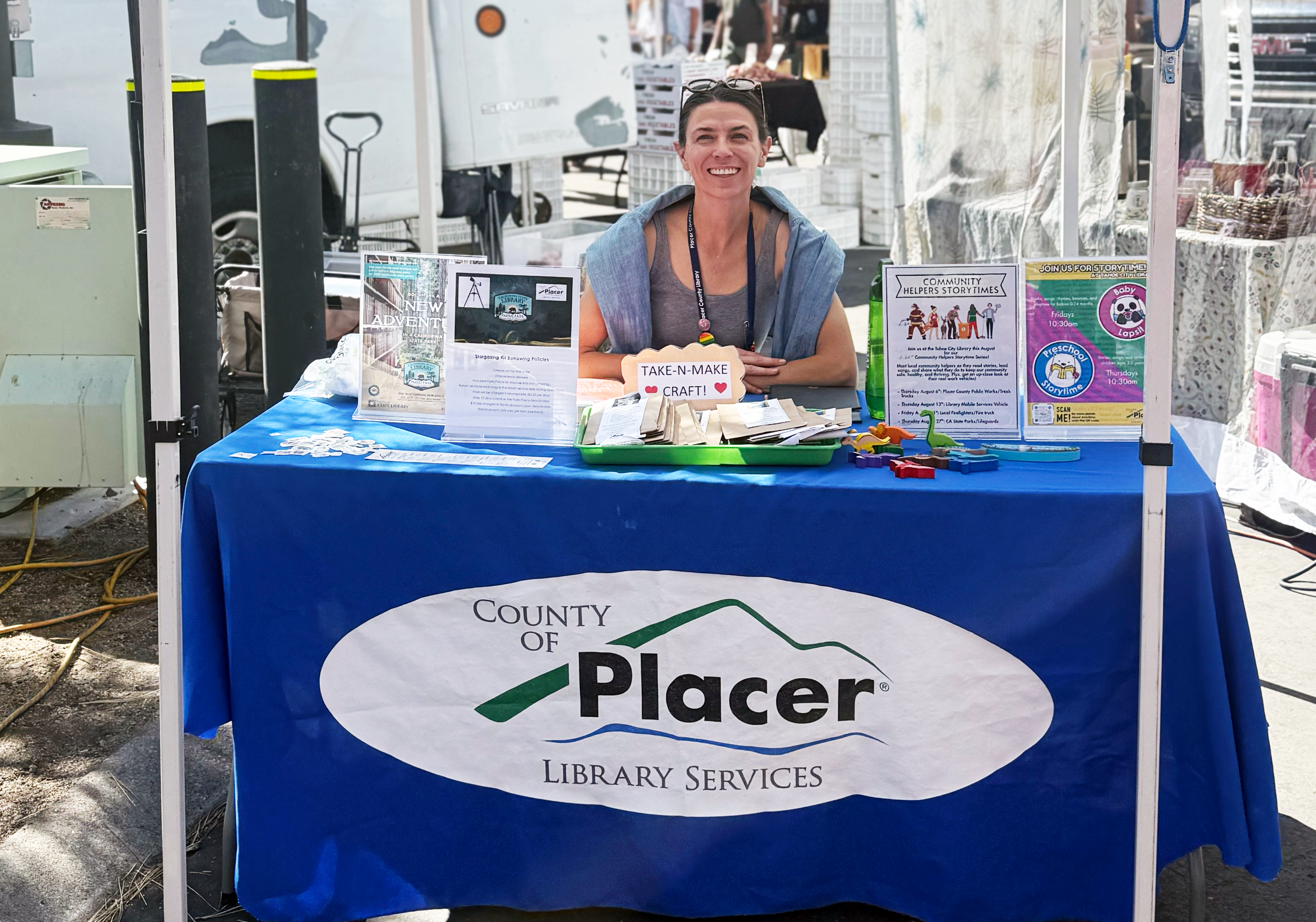 Placer County Library card in front of a stack of children's books on a wooden surface.