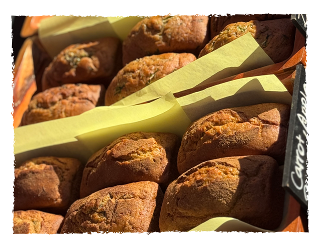 Close-up of fresh baked muffins with a yellow paper liner in a bakery display.
