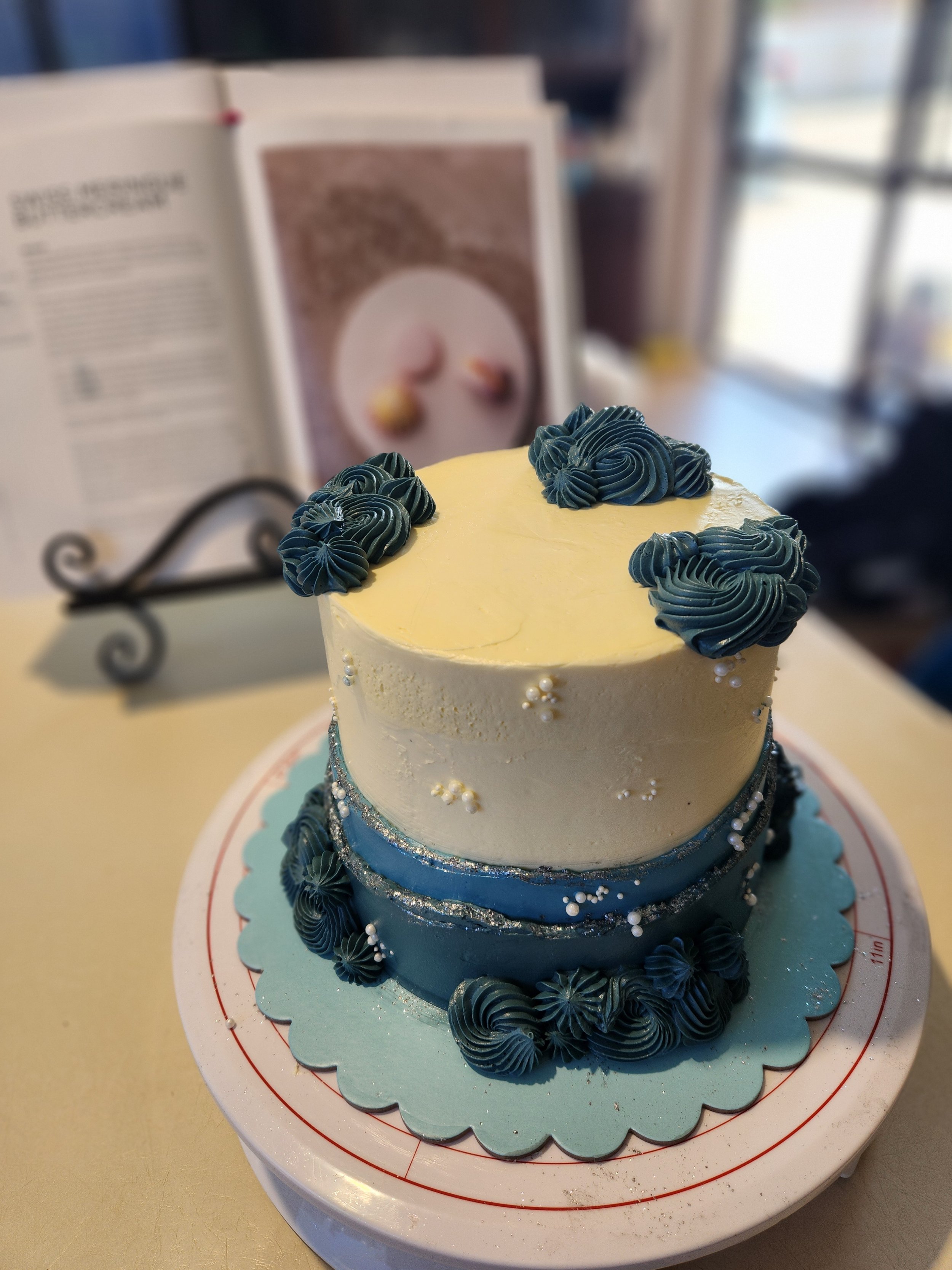 6 Inch birthday cake with dark blue and white decorations, piped frosting, and small white sugar pearls. Feeds 12-24 depending on serving size.