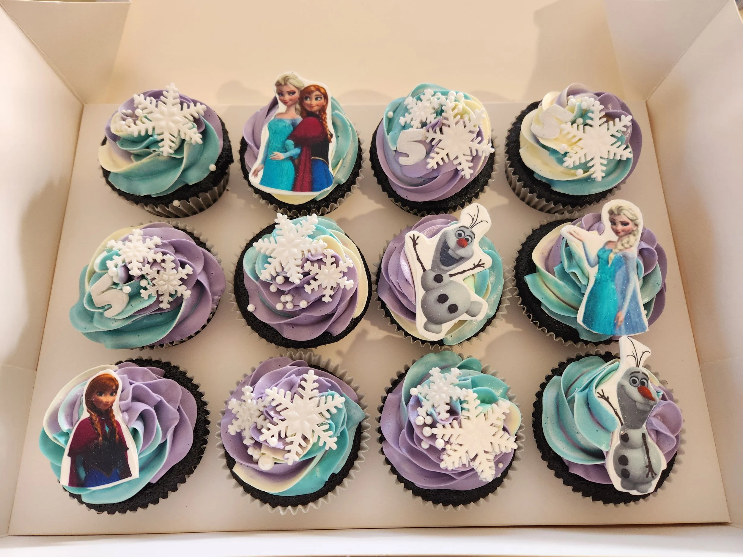 Frozen-themed cupcakes decorated in soft blue and white buttercream, finished with snowflake details and themed toppers. A simple, magical option for any Frozen fan.