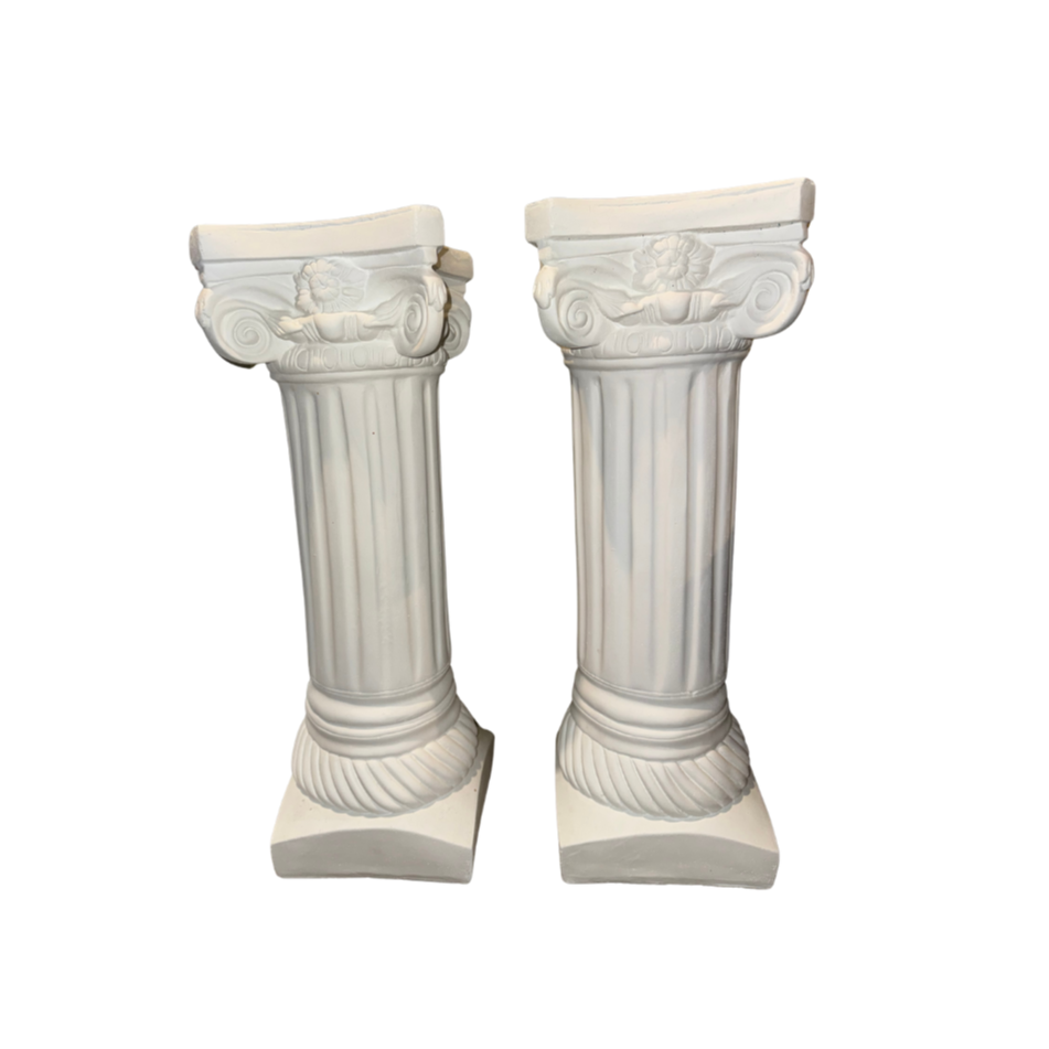 Two white decorative classical-style columns with floral and scroll details on top.