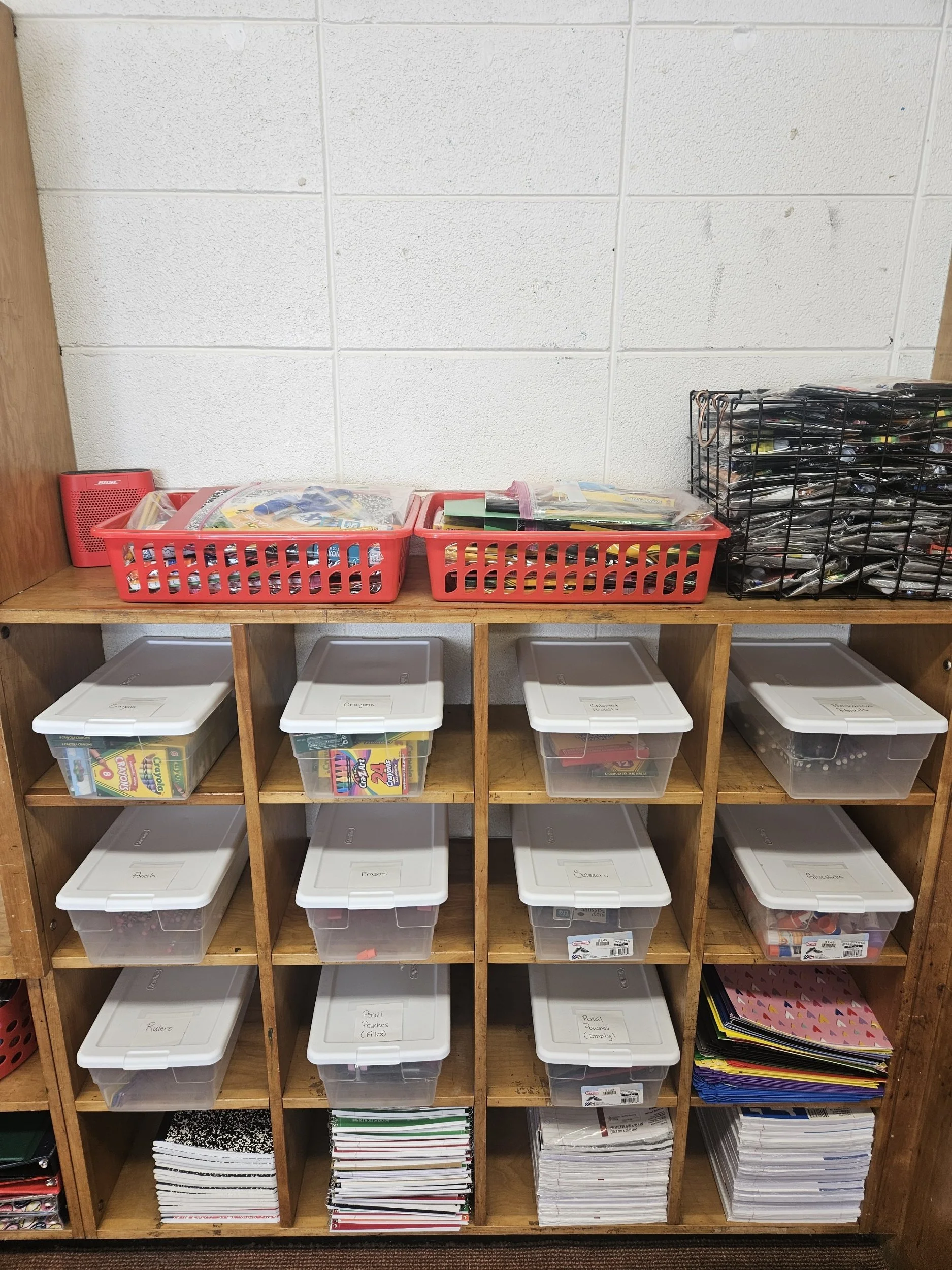 Storage bins filled with school supplies on shelves.