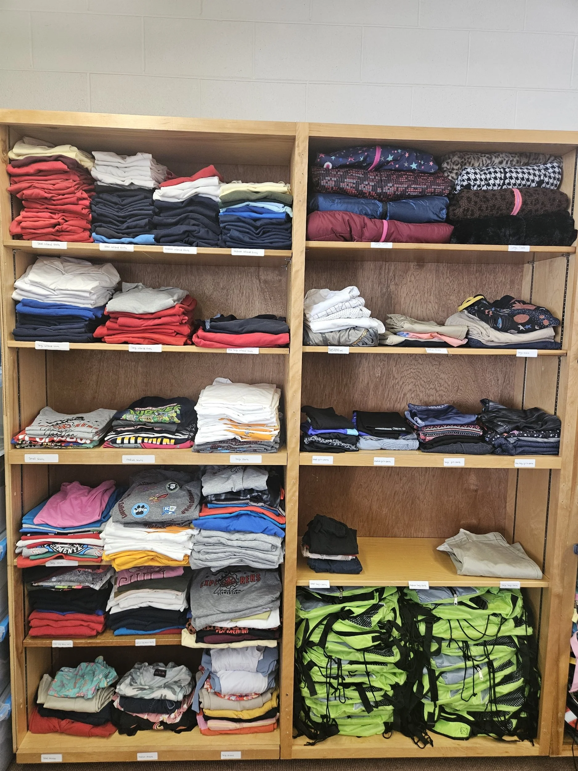 Folded clothing and bags on shelves.