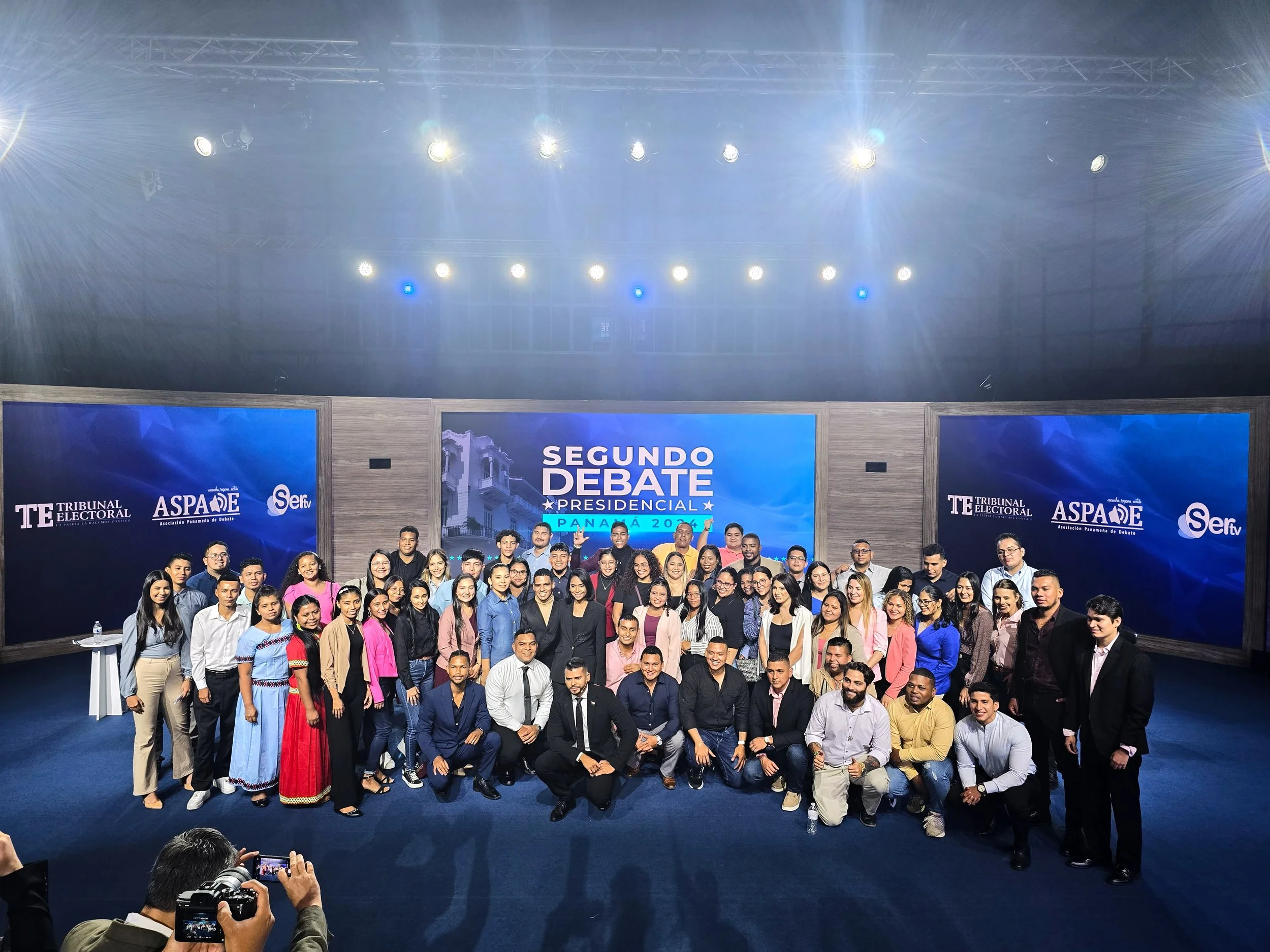 Grupo de personas en un escenario durante un debate presidencial en Panamá en 2024, con pantallas y logotipos relacionados con el evento.